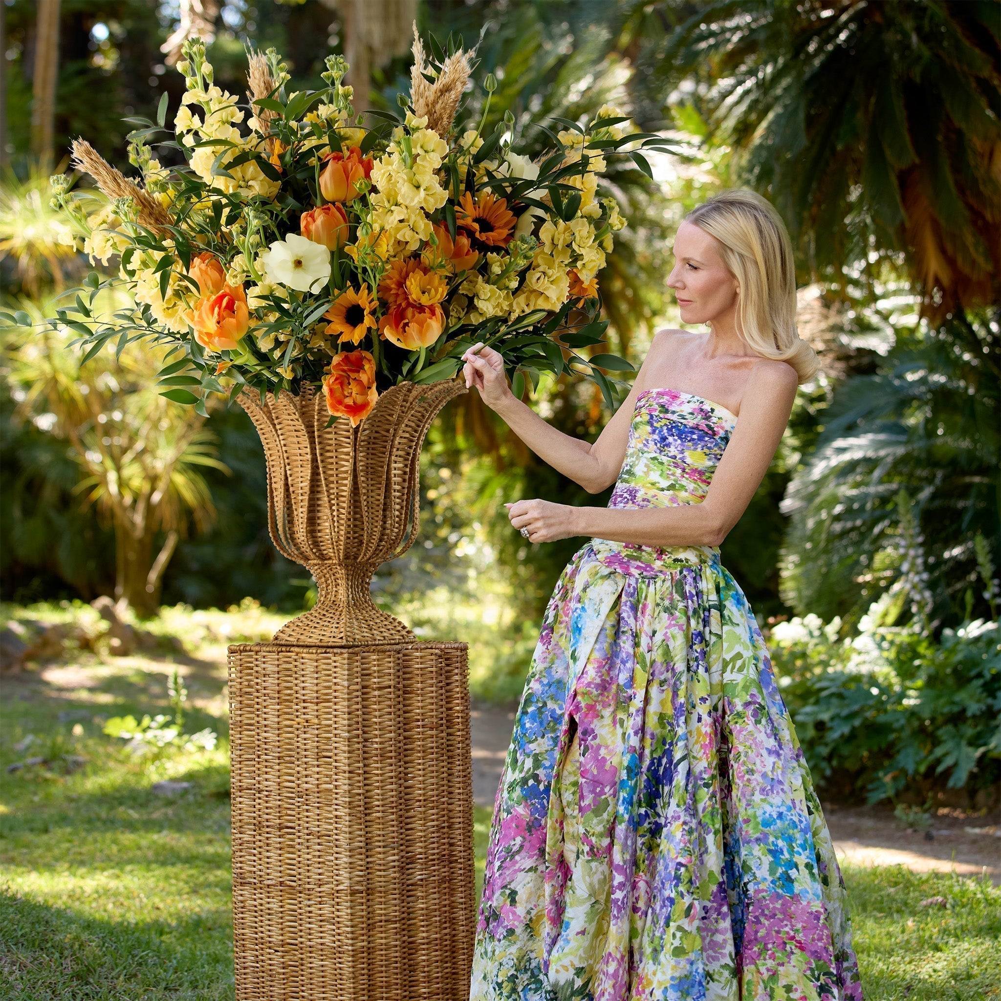 Premium Grade-A natural rattan column plinth and matching woven urn vase styled outdoors for an upscale garden gathering.
