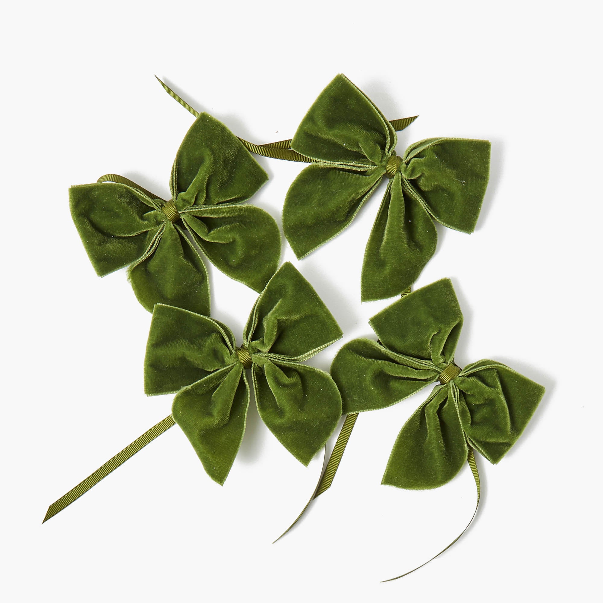 A set of four forest green velvet napkin bows arranged on a white background.