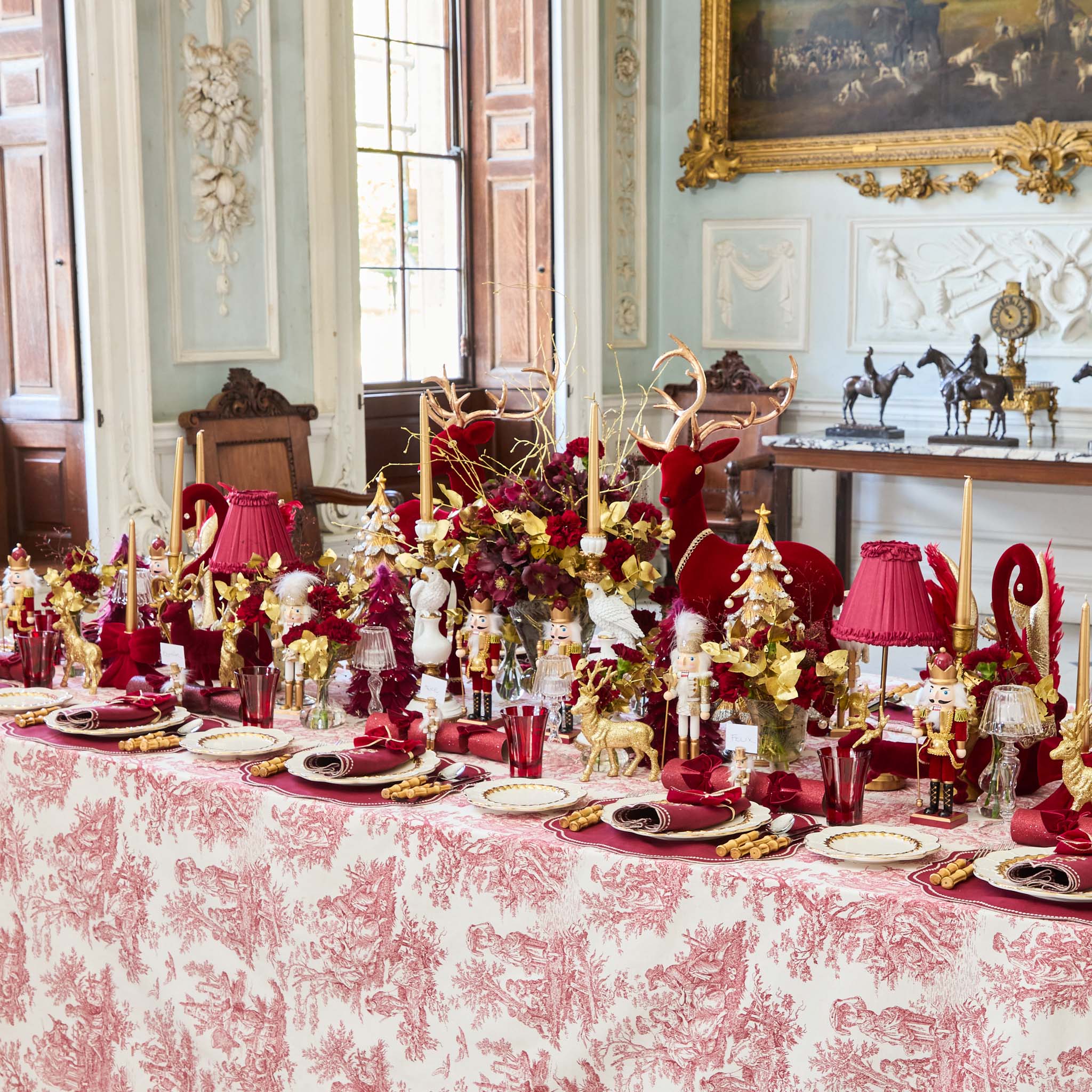 Decorative Christmas table setting with red and gold theme in an elegant room.