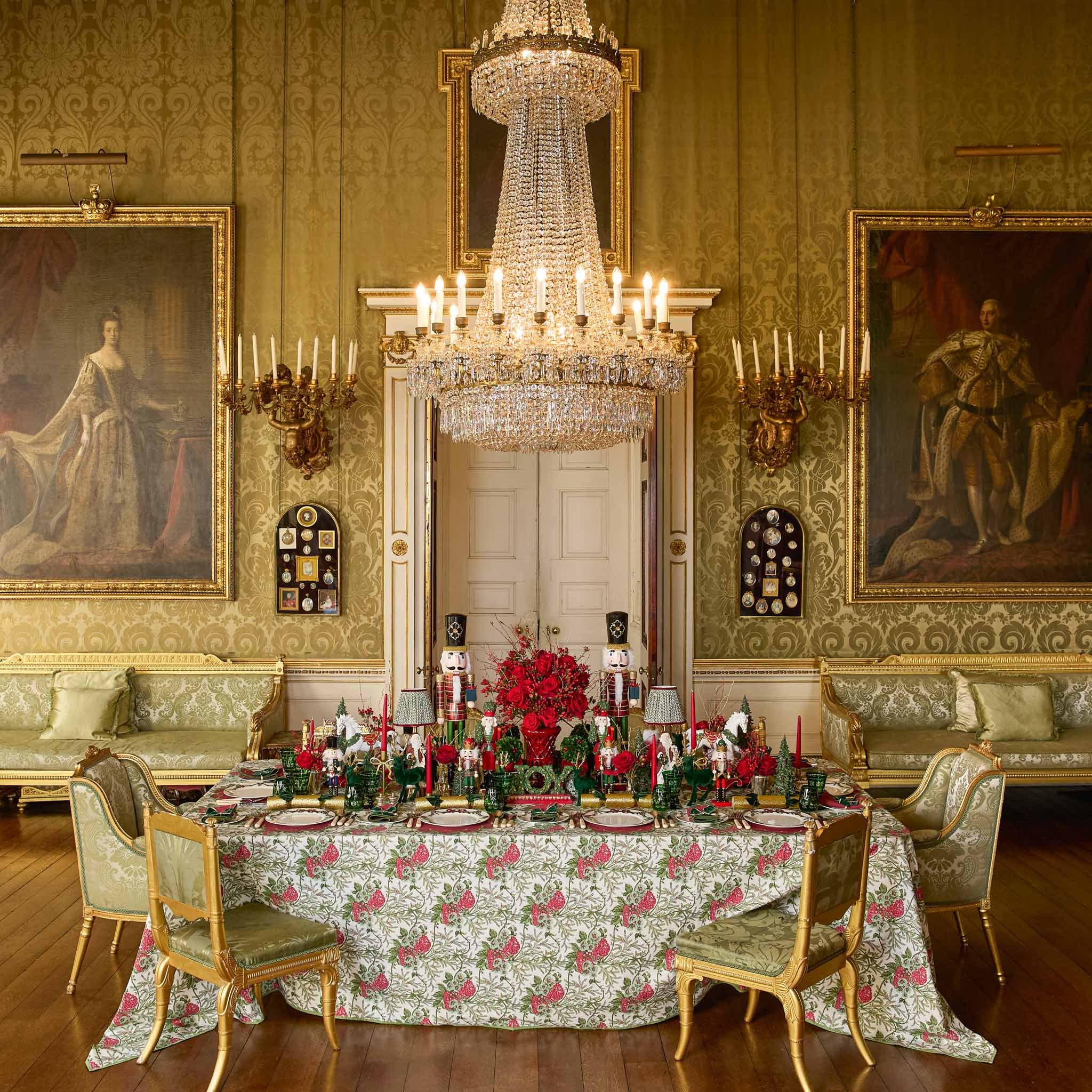 Decorative dining room with ornate table setting, chandelier, and classical paintings.