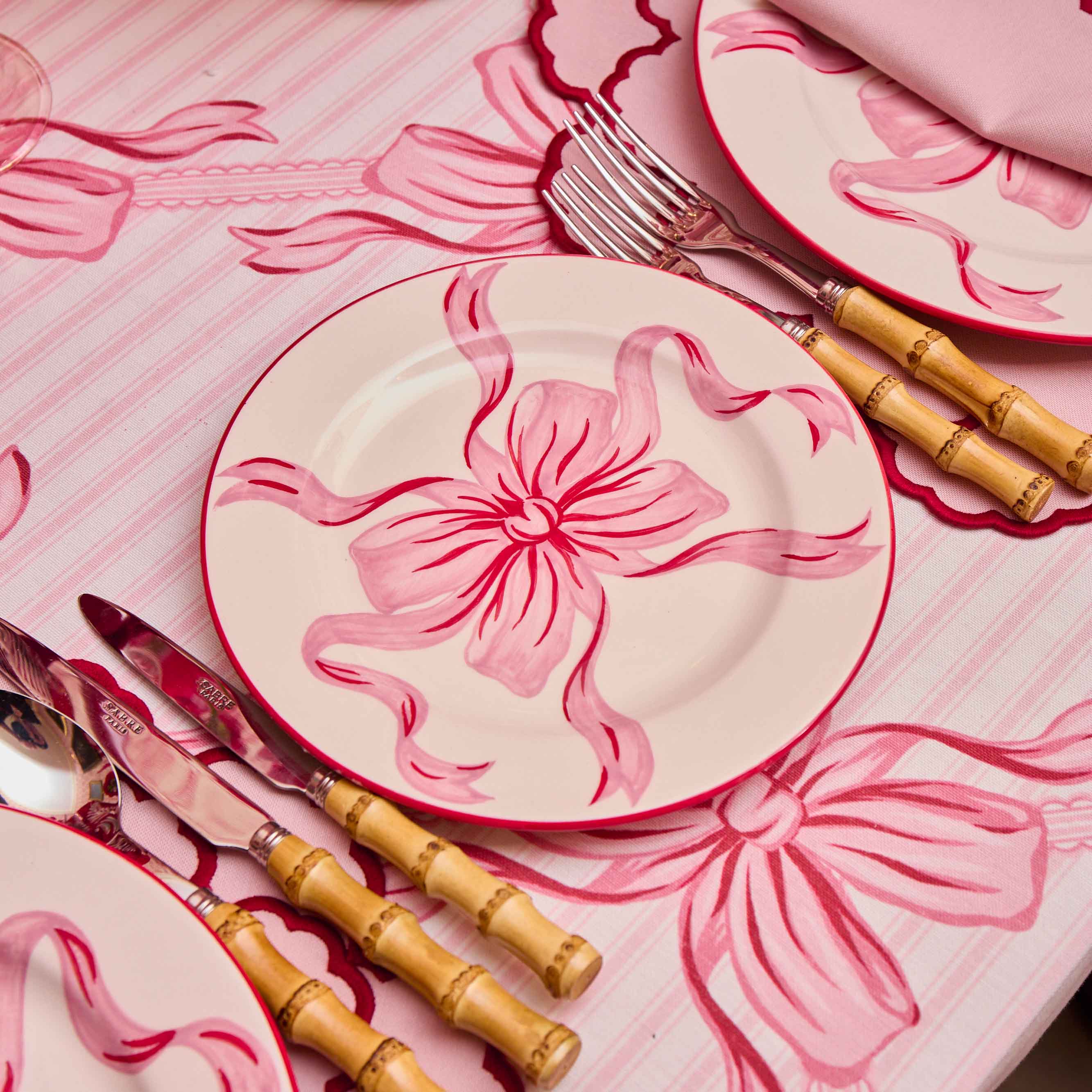Dinner set with pink flamingo design on plates, cutlery, and a matching tablecloth.