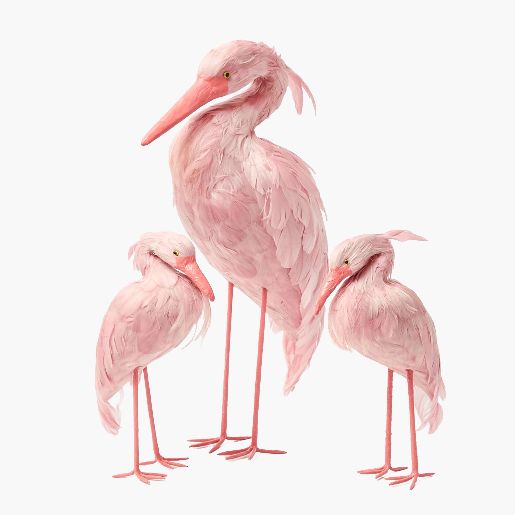 Three pink flamingo figurines on a white background