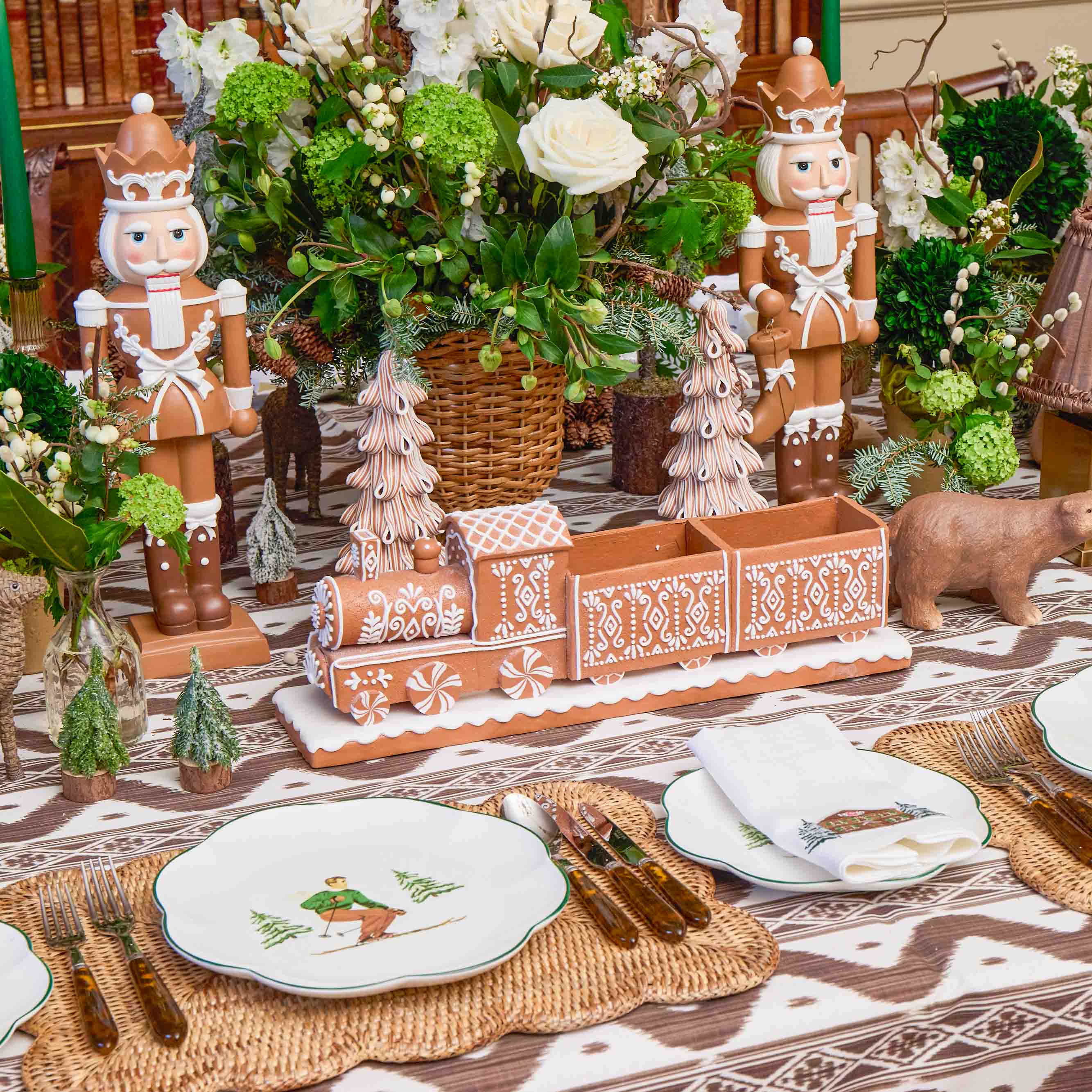 Decorative table setting with gingerbread men, train, and Christmas-themed plates.