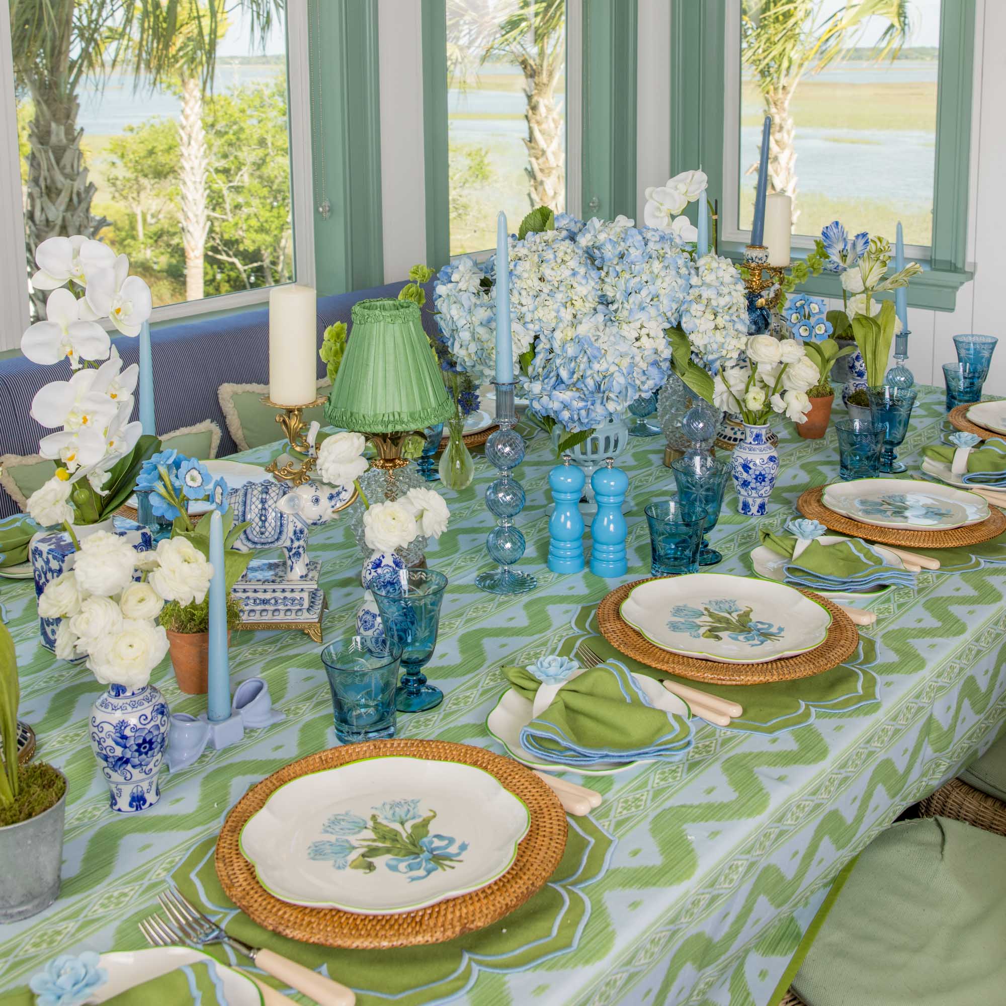Decorative table setting with floral arrangements and colorful tableware in a bright room.