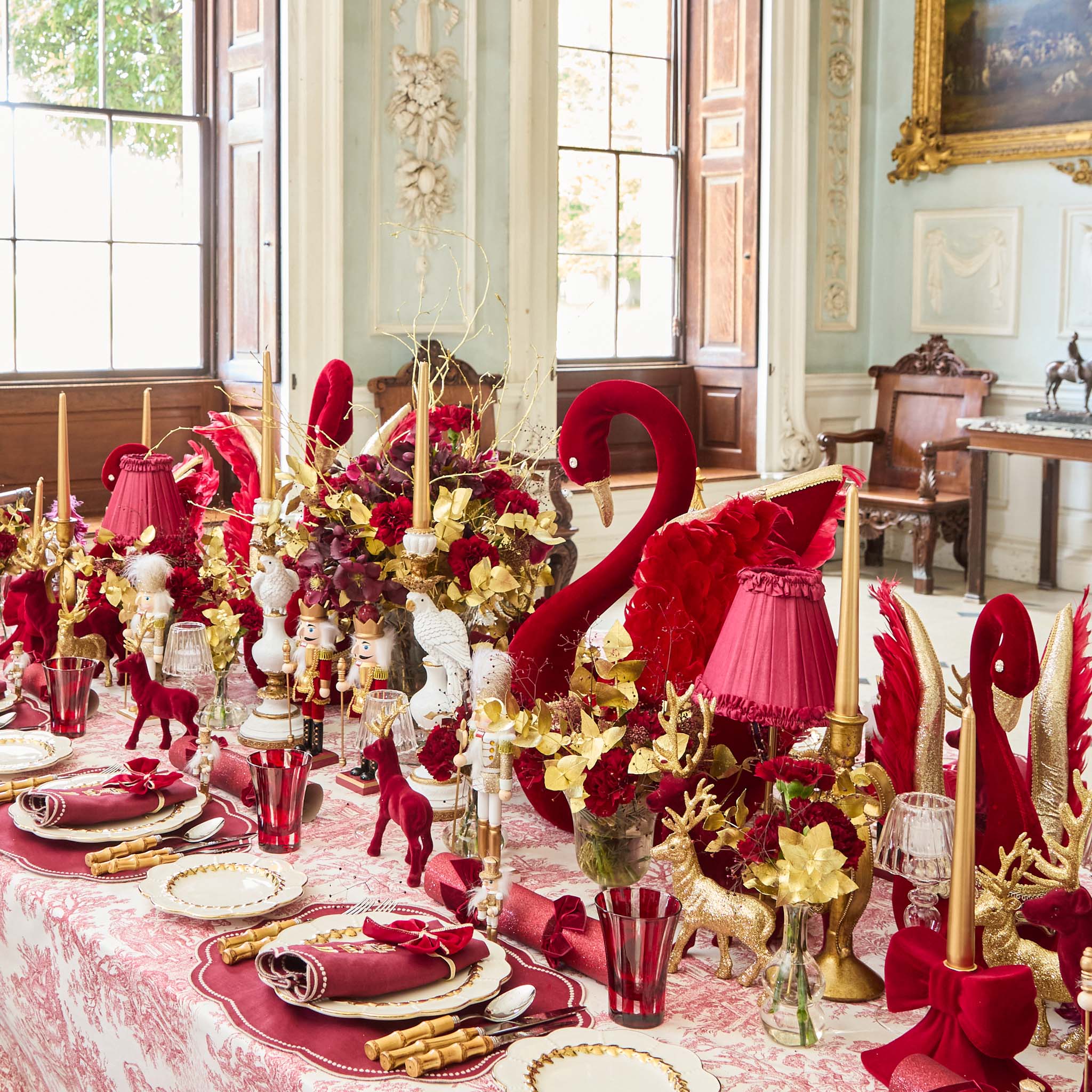Decorative table setting with red and gold elements in a formal dining room.