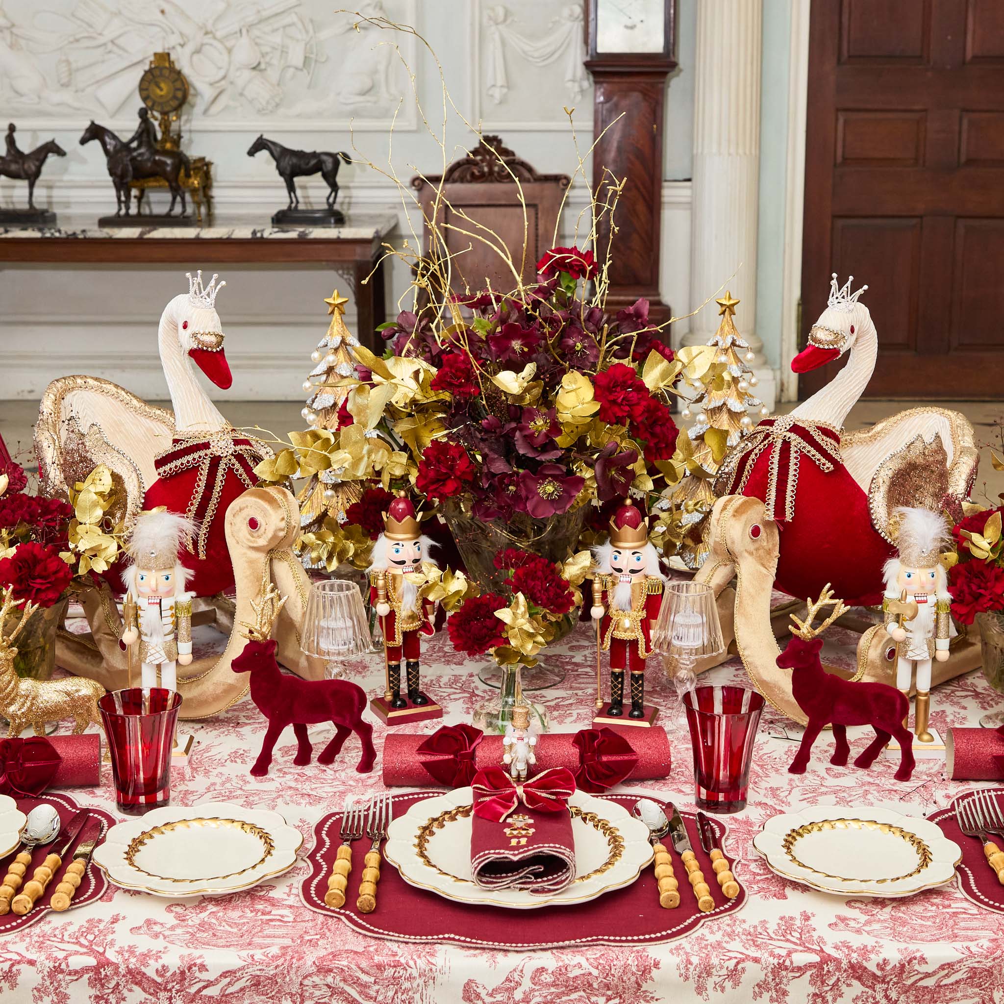 Decorative Christmas table setting with swans, nutcrackers, and red accents.