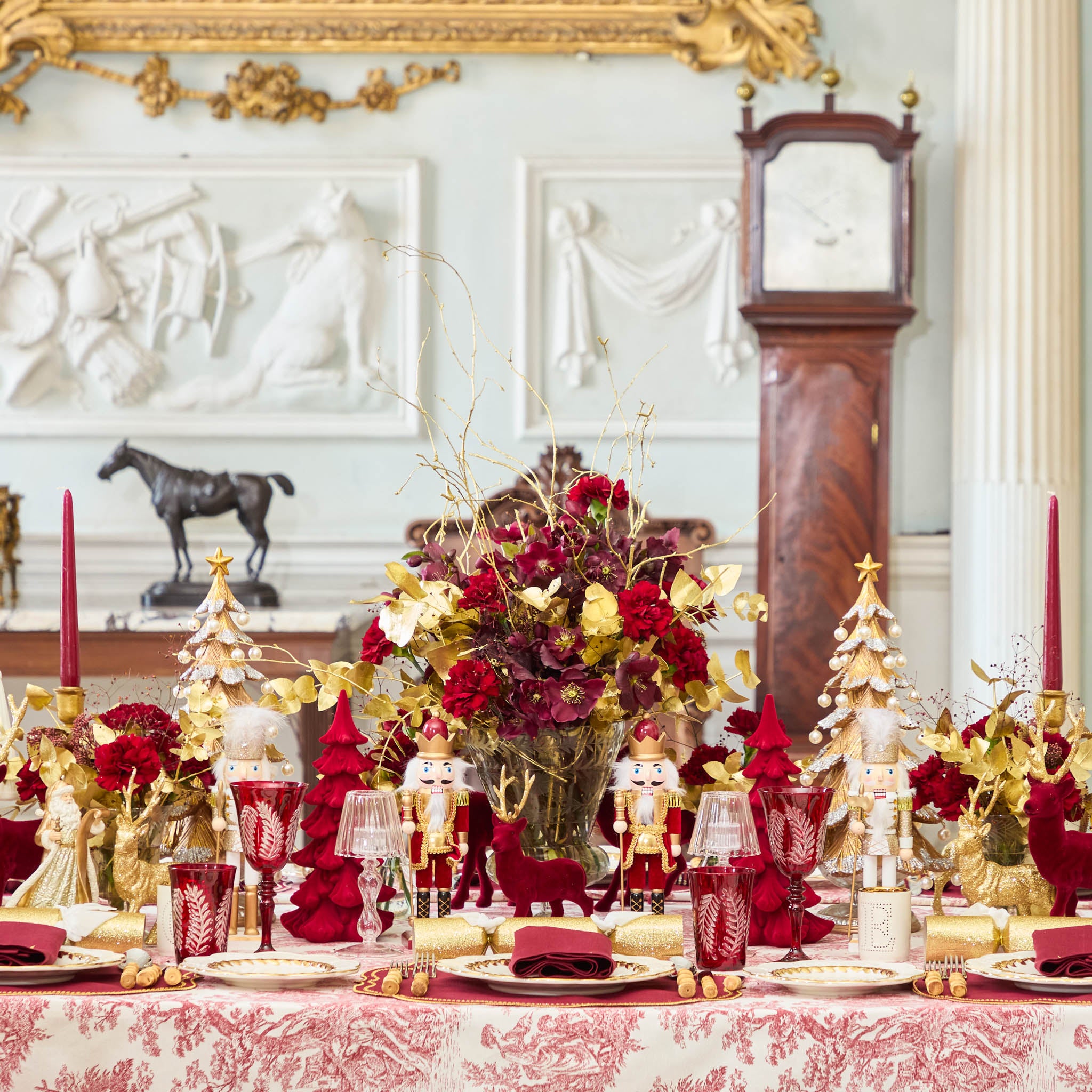 Decorative Christmas table setting with red and gold elements in a formal room.