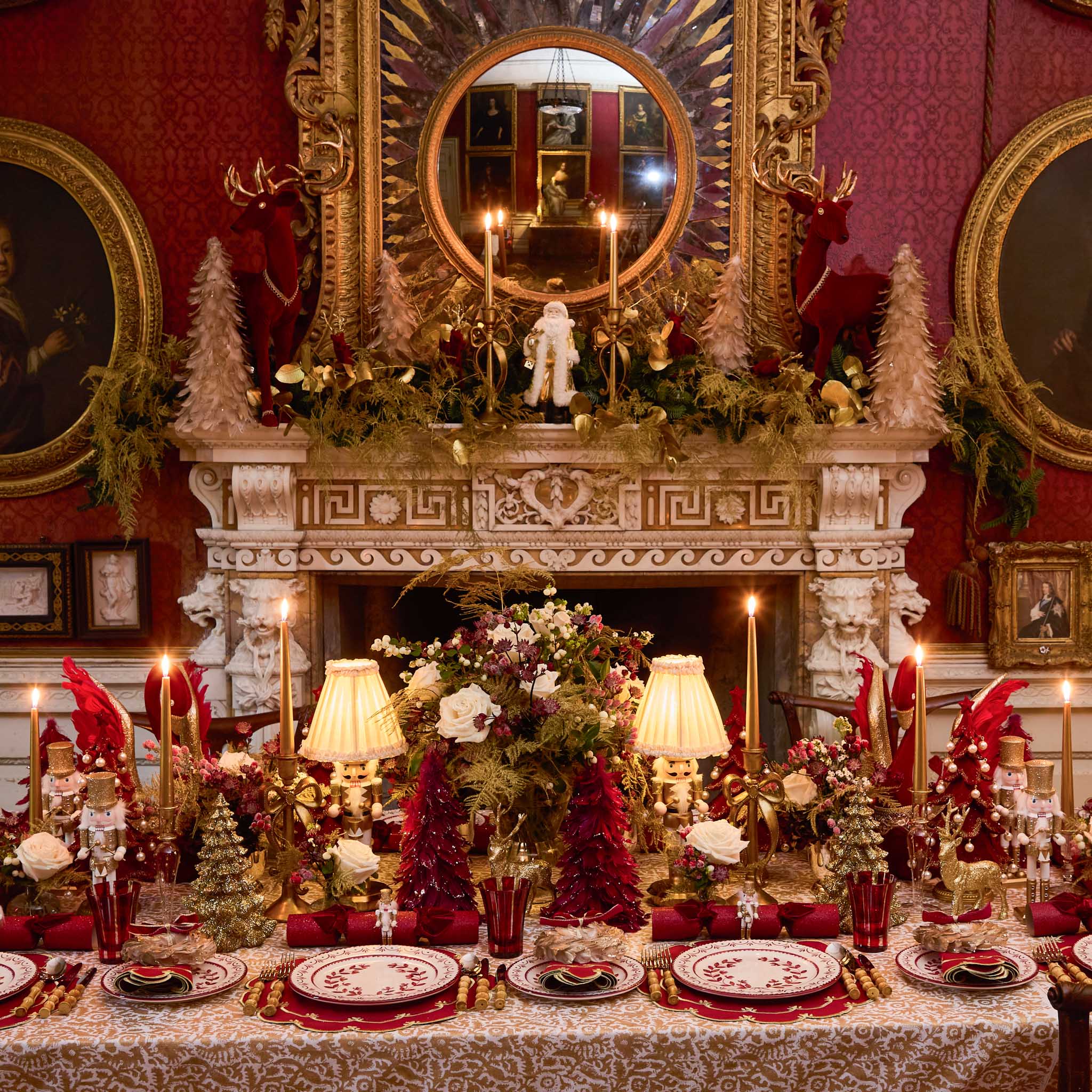 Decorative Christmas table setting with red and gold accents in a grand room.