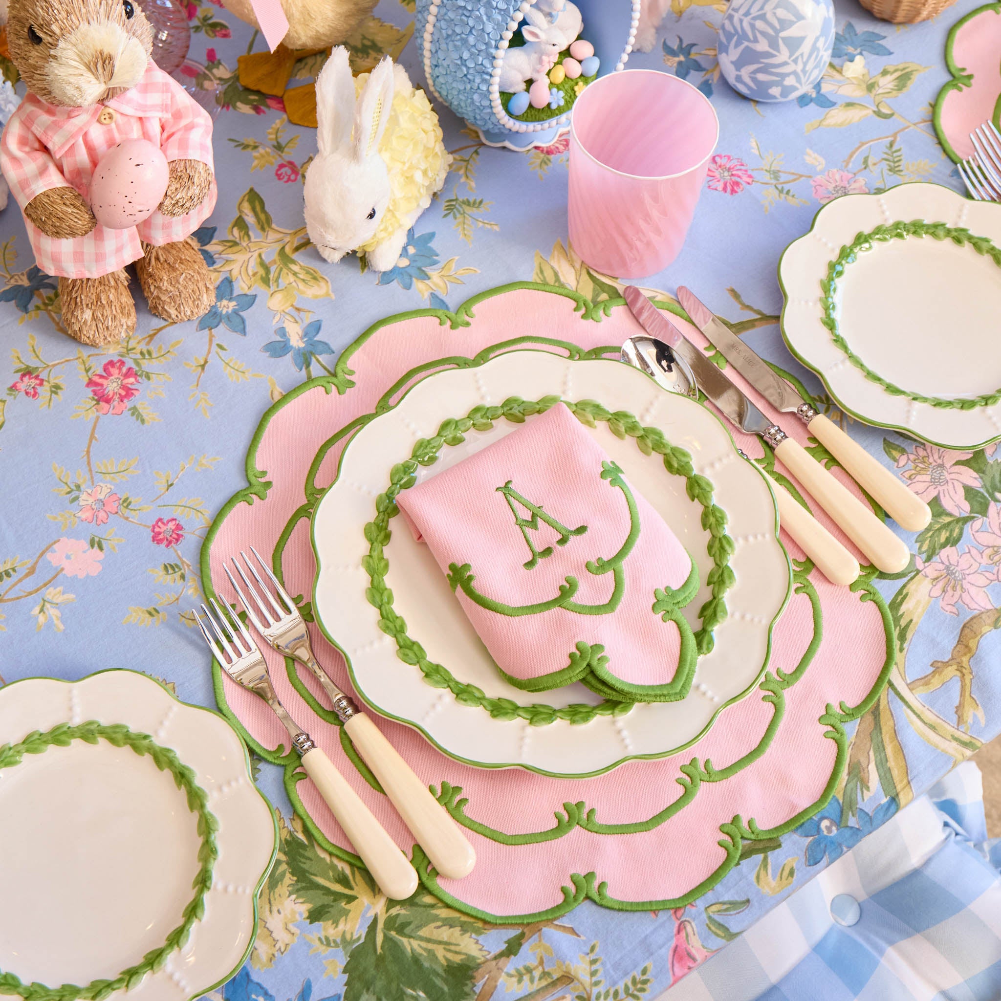 Easter-themed table setting with pink and green decorations on a floral tablecloth.