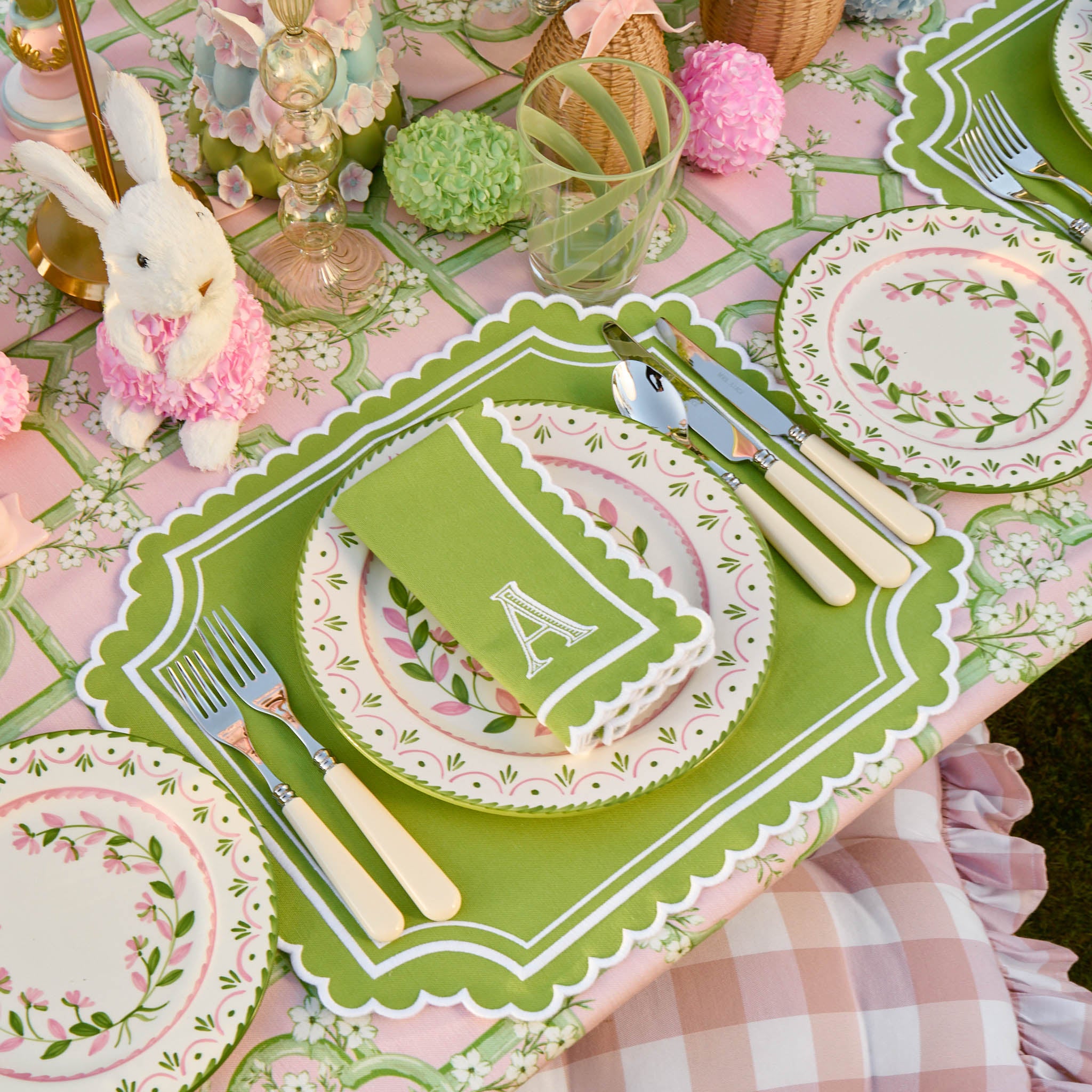 Easter-themed table setting with green placemat, floral plates, and bunny decorations.