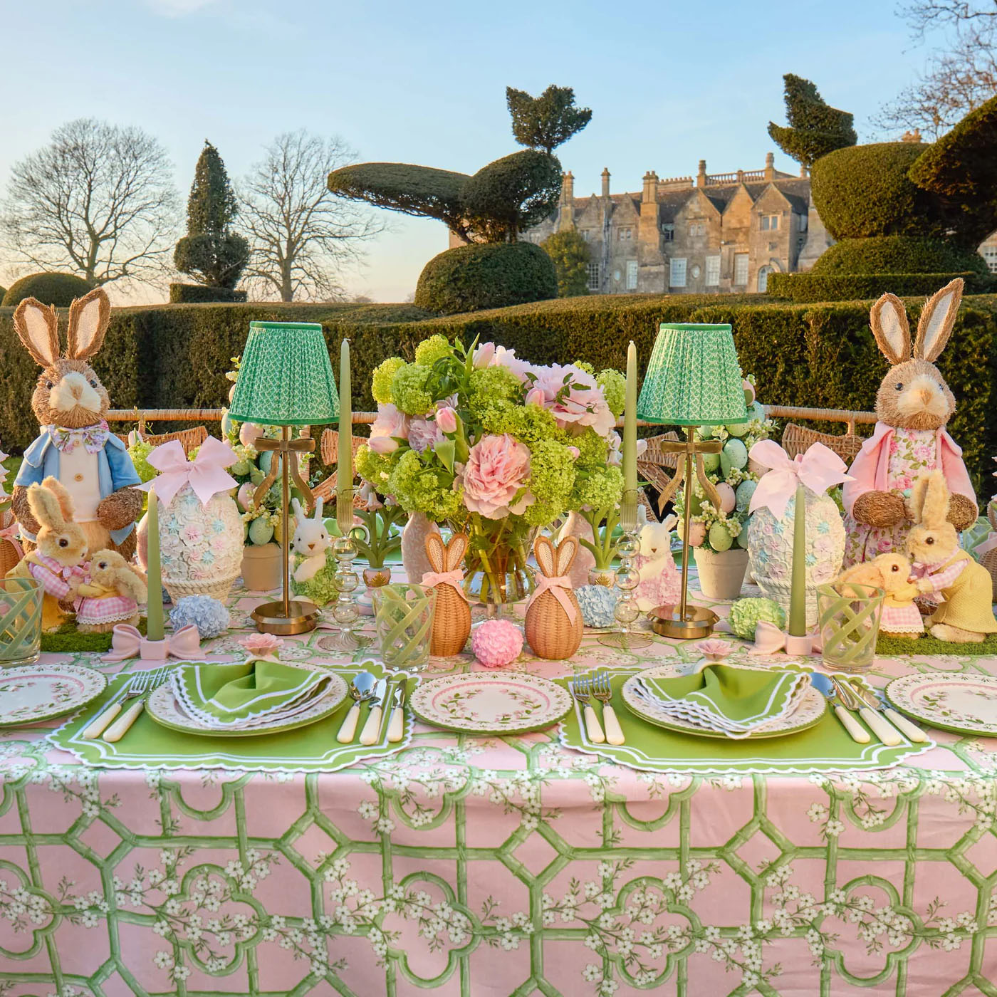 Easter-themed table setting with decorative bunnies and floral arrangements outdoors.