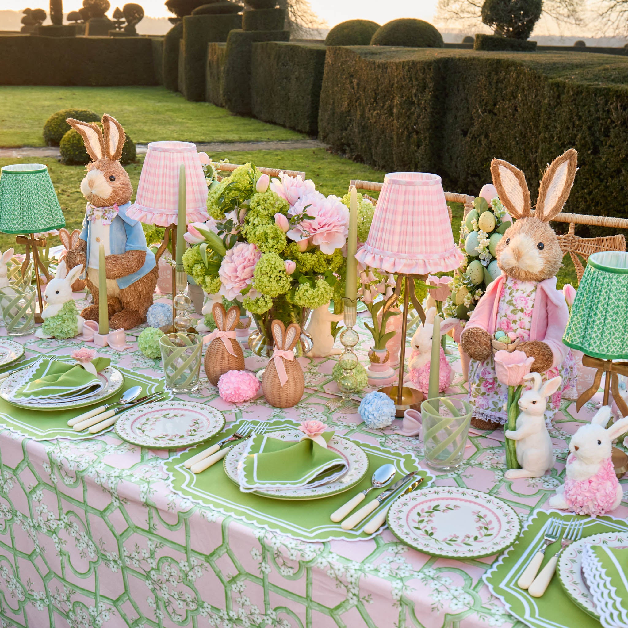Easter-themed table setting with decorative rabbits and floral arrangements outdoors.