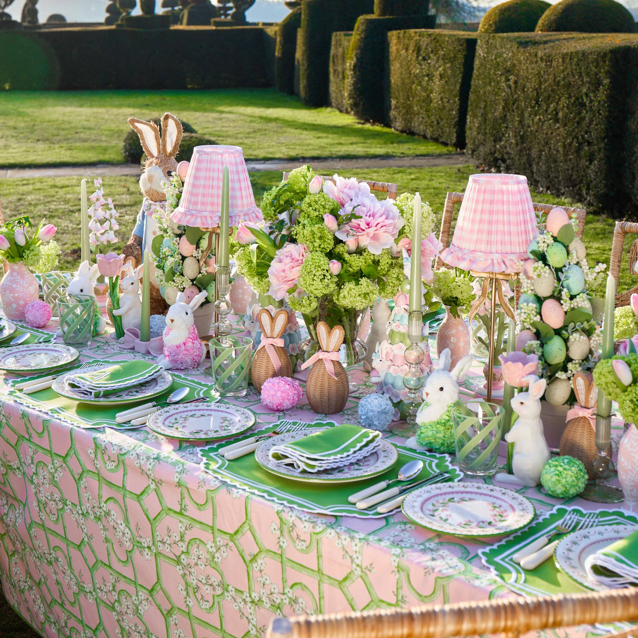 Easter-themed table setting with bunny decorations and floral arrangements outdoors.