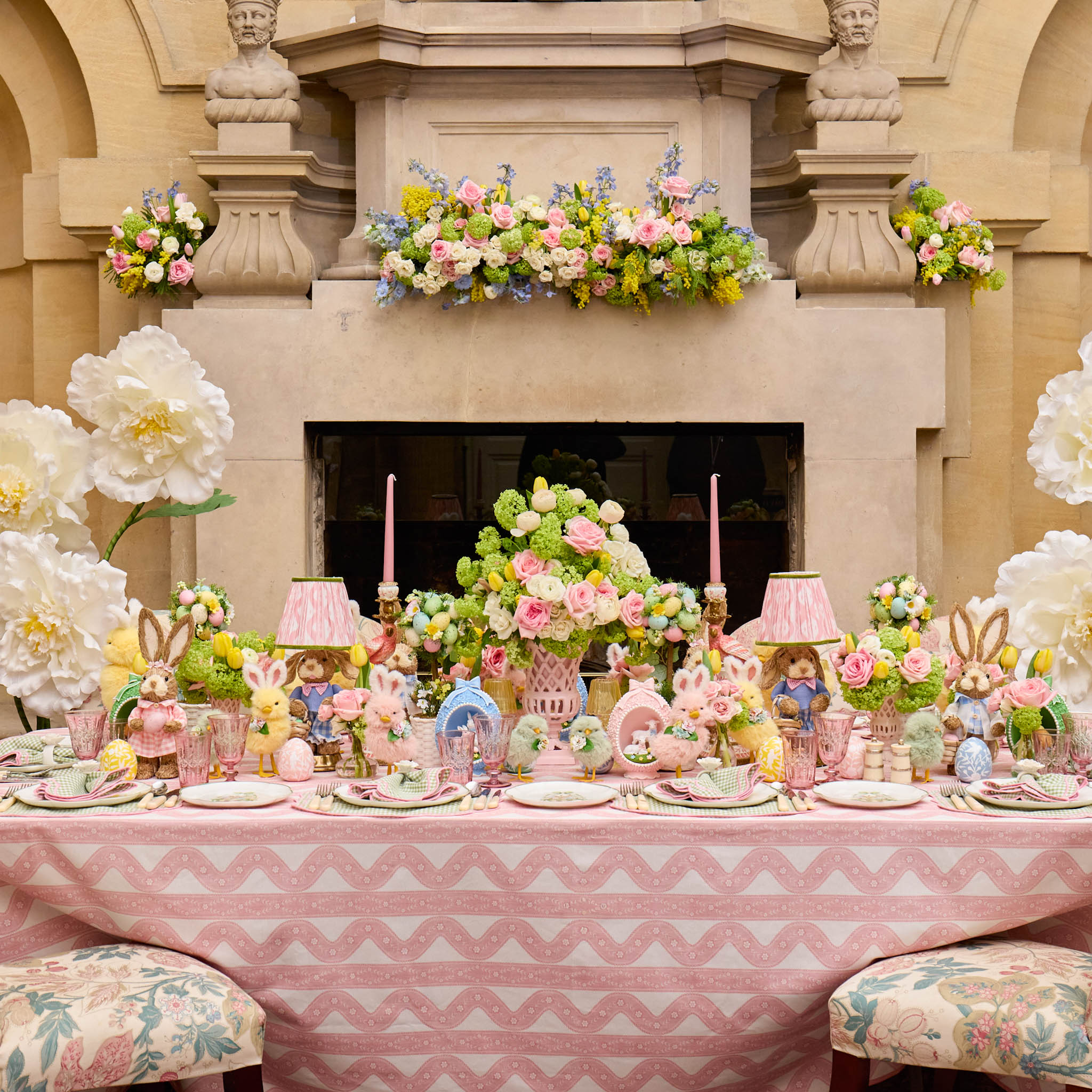 Decorative Easter table setting with flowers, pastel colors, and small figurines in a formal setting.