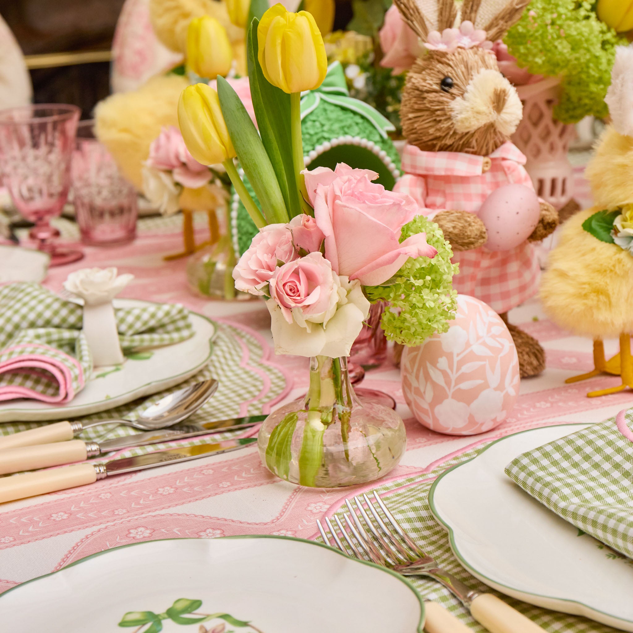 Easter-themed table setting with floral centerpieces, bunny figurines, and decorative eggs.