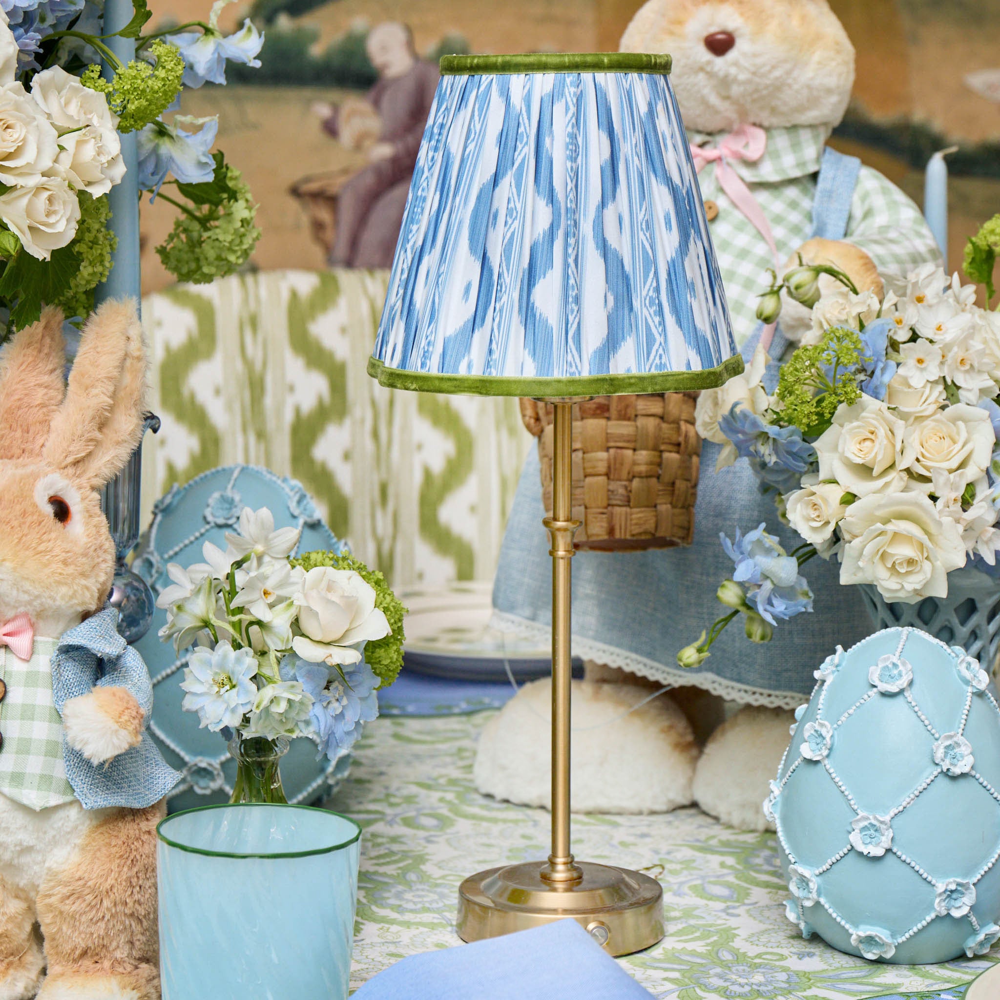 Decorative scene with a lamp, flowers, and plush toys in a cozy setting.