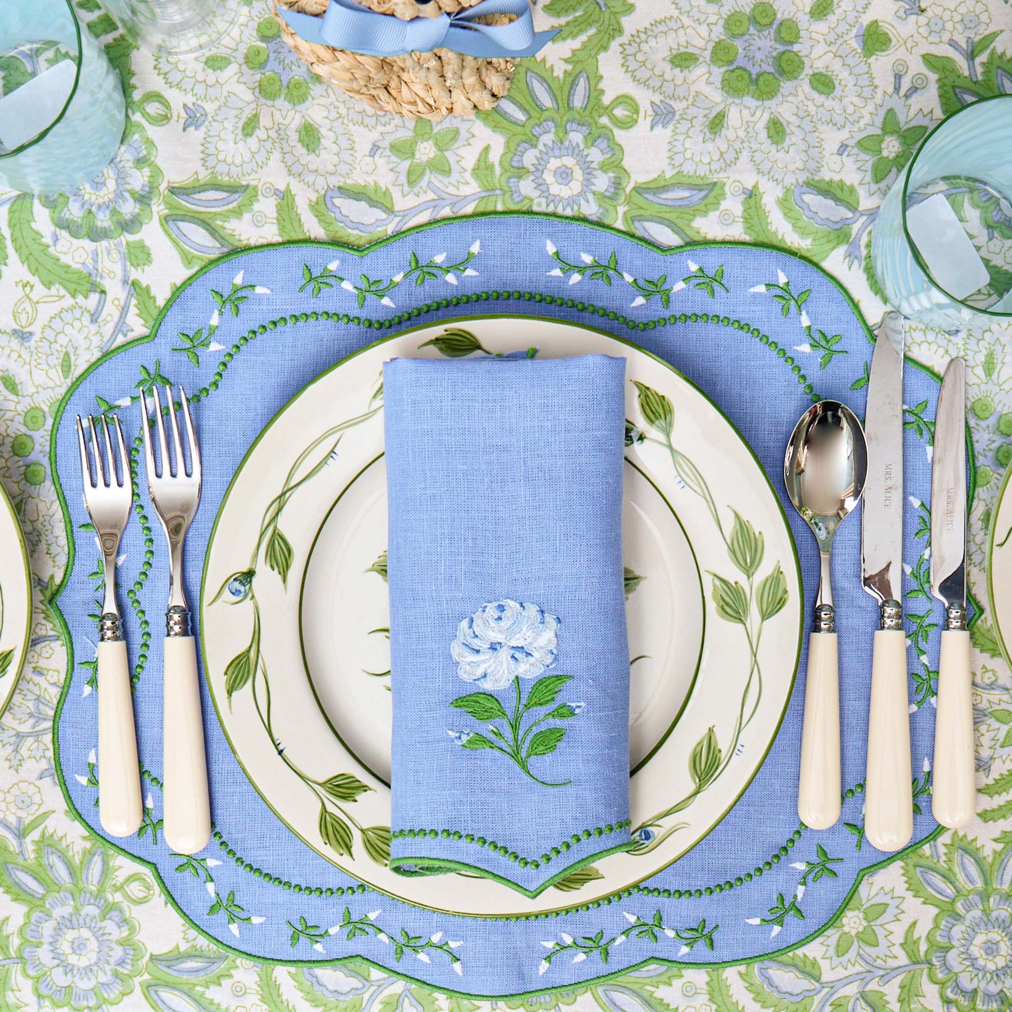 Table setting with blue and green floral patterns on plates, napkin, and placemat.