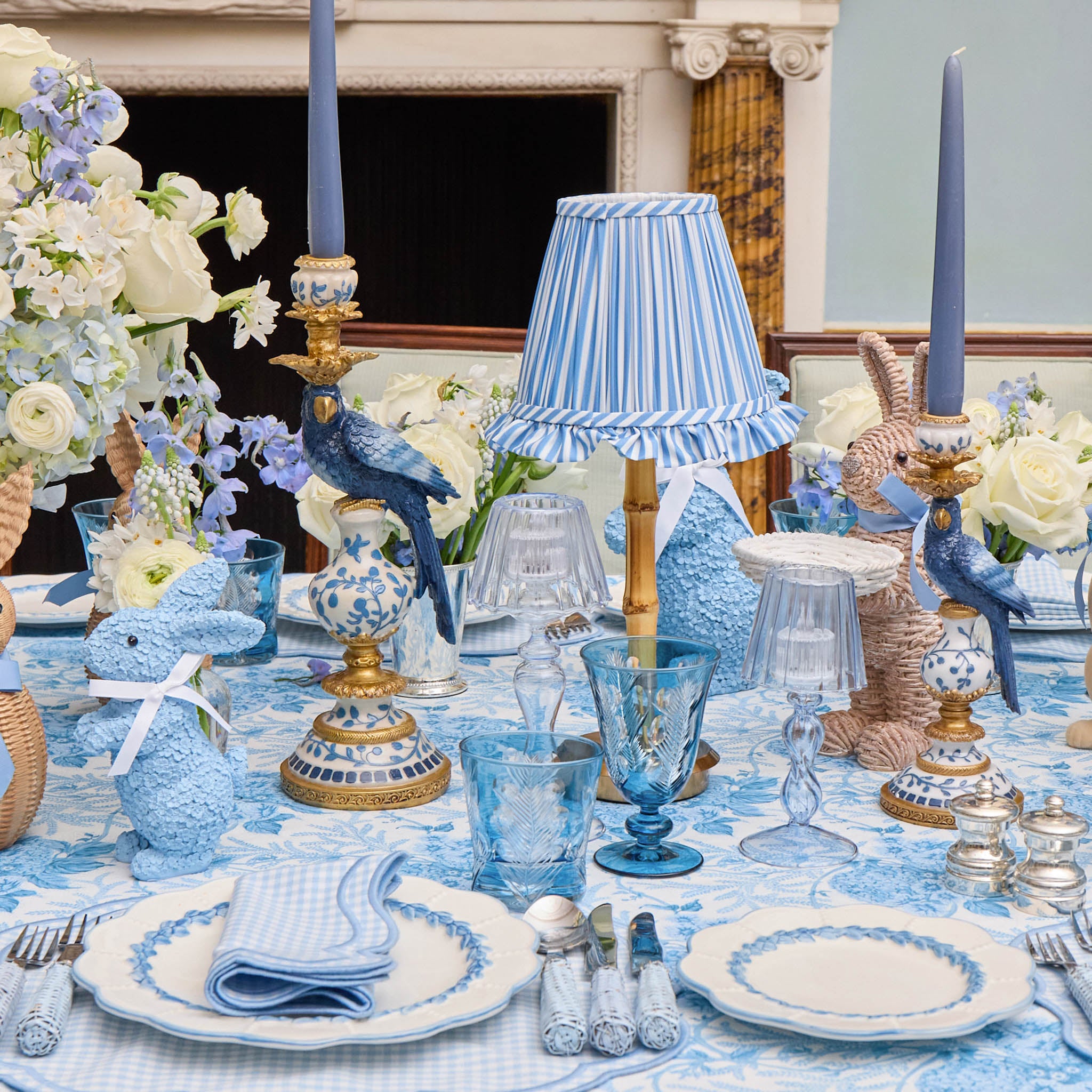 Elegant table setting with blue and white decor, including flowers and tableware.