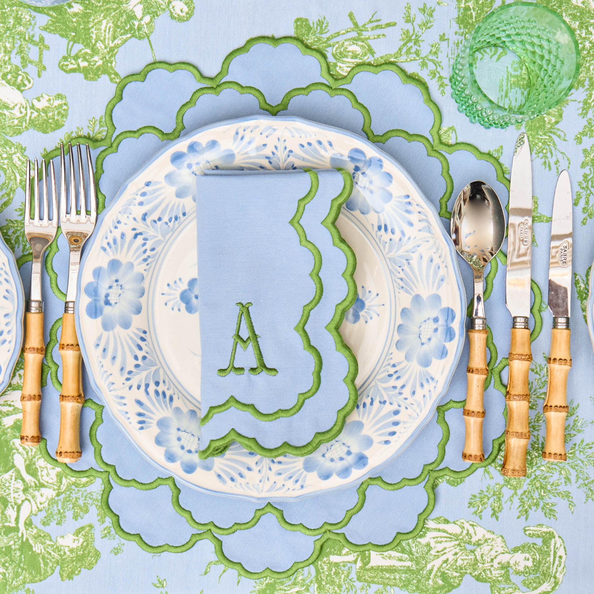 Decorative table setting with a plate, cutlery, and place mat on a patterned tablecloth.