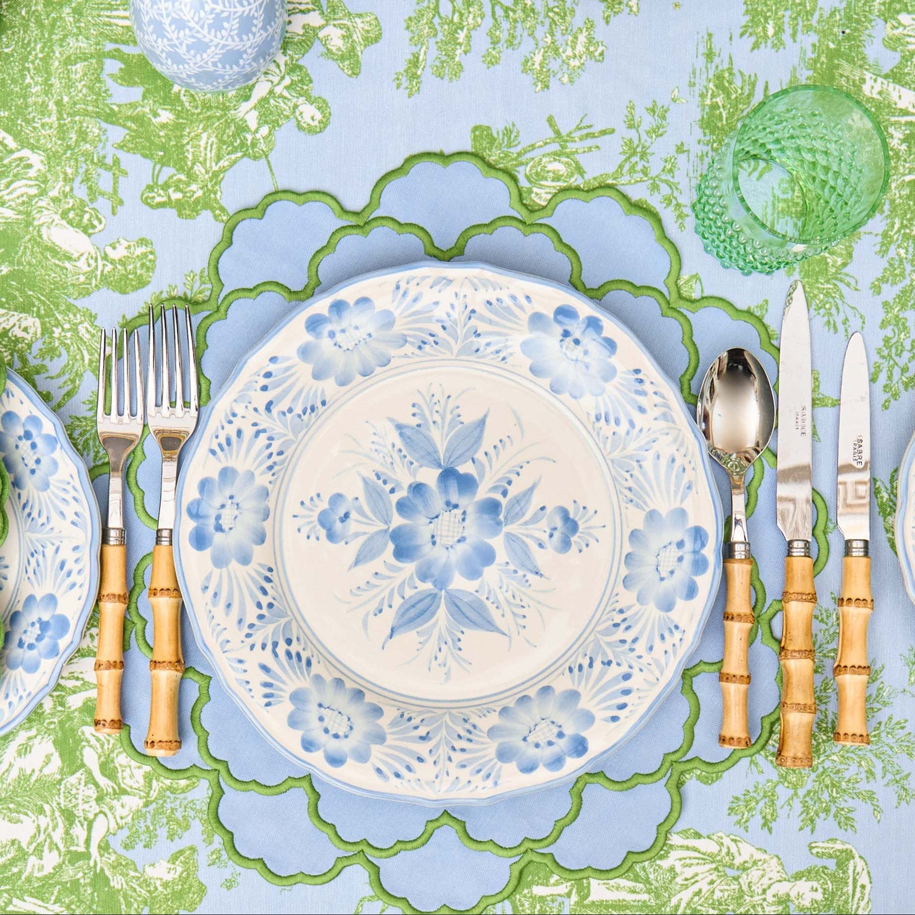 Decorative table setting with floral plates, cutlery, and a patterned tablecloth.
