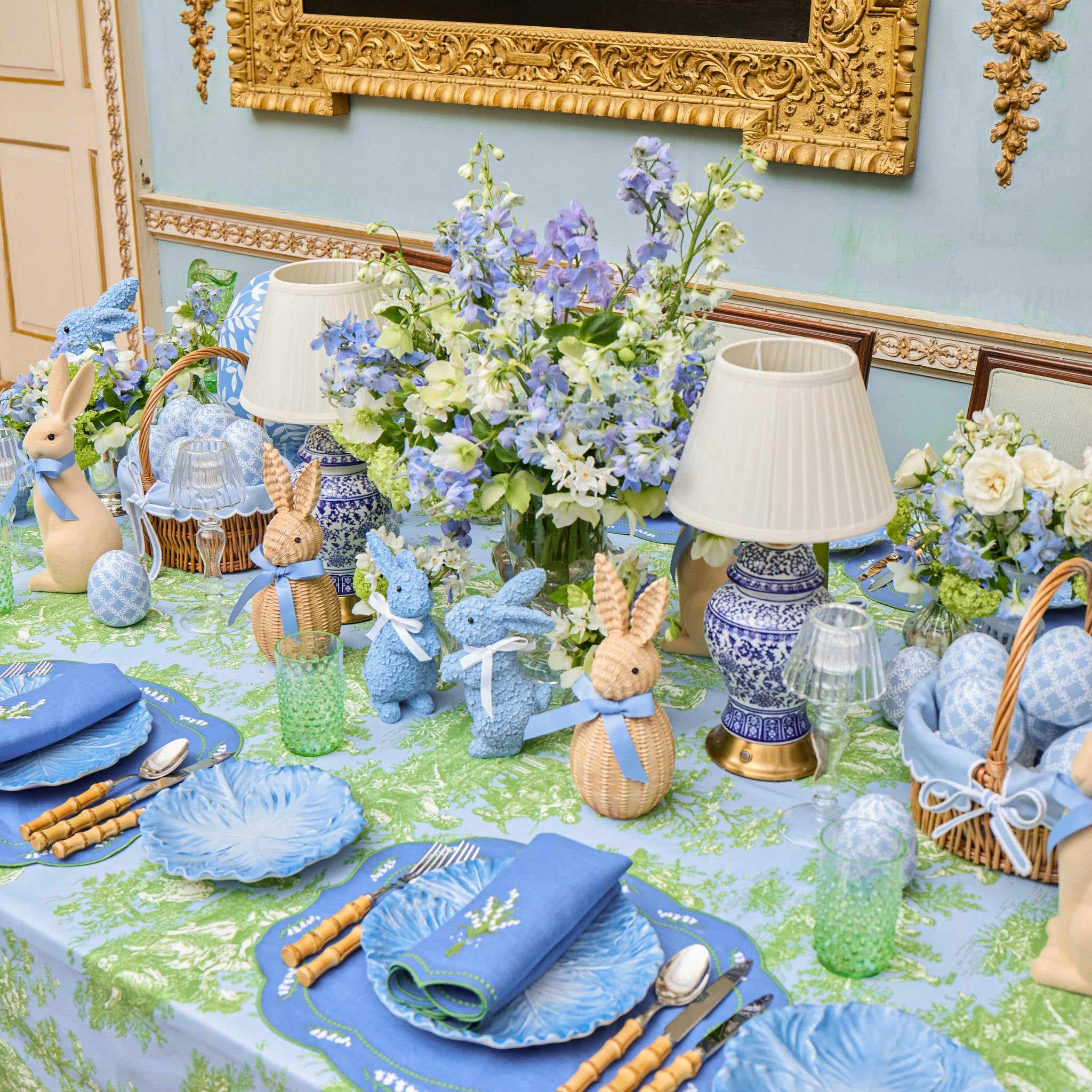 Easter-themed table setting with blue and green decorations, including bunny figurines and floral arrangements.