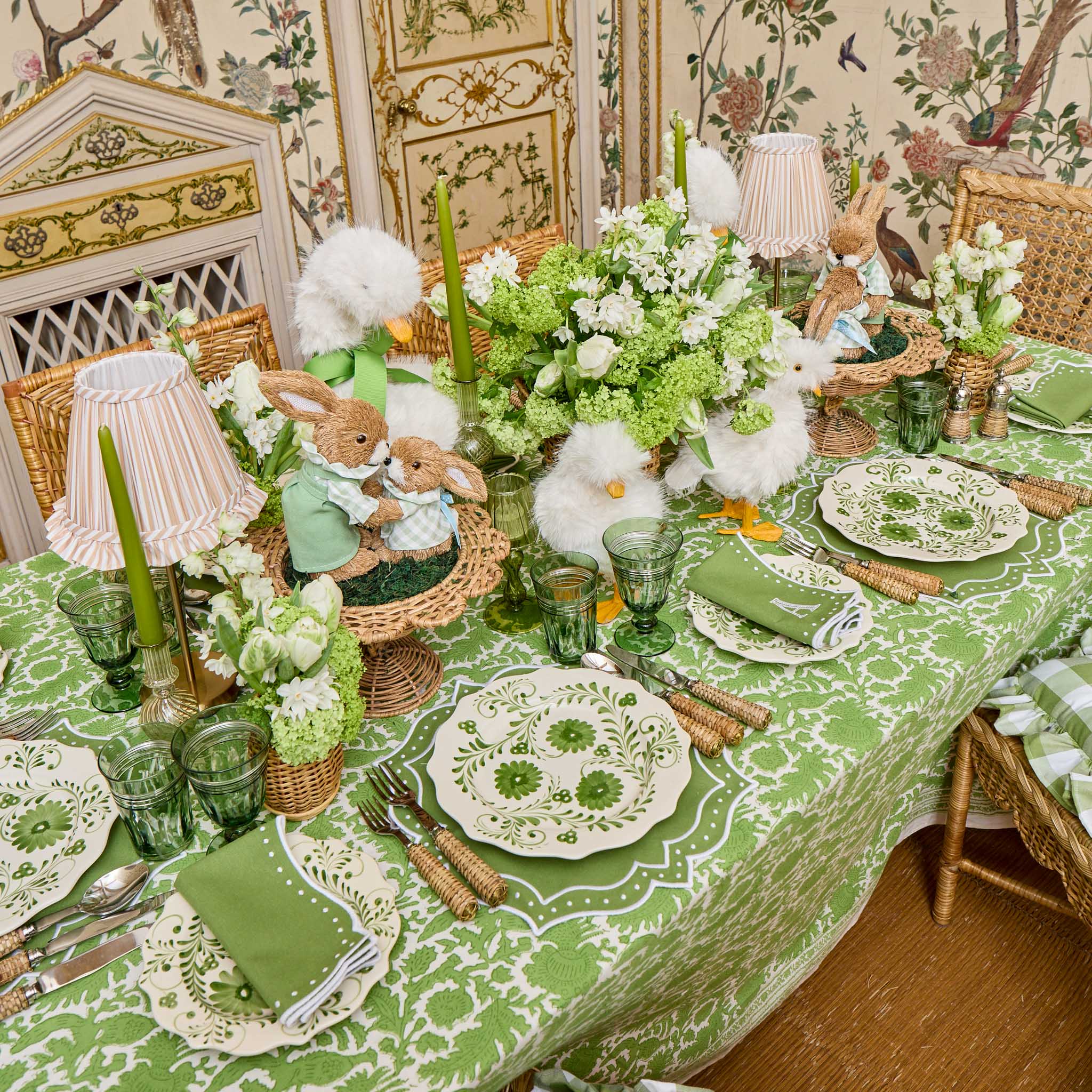 Easter-themed table setting with green and white decor, including bunny figurines and floral arrangements.