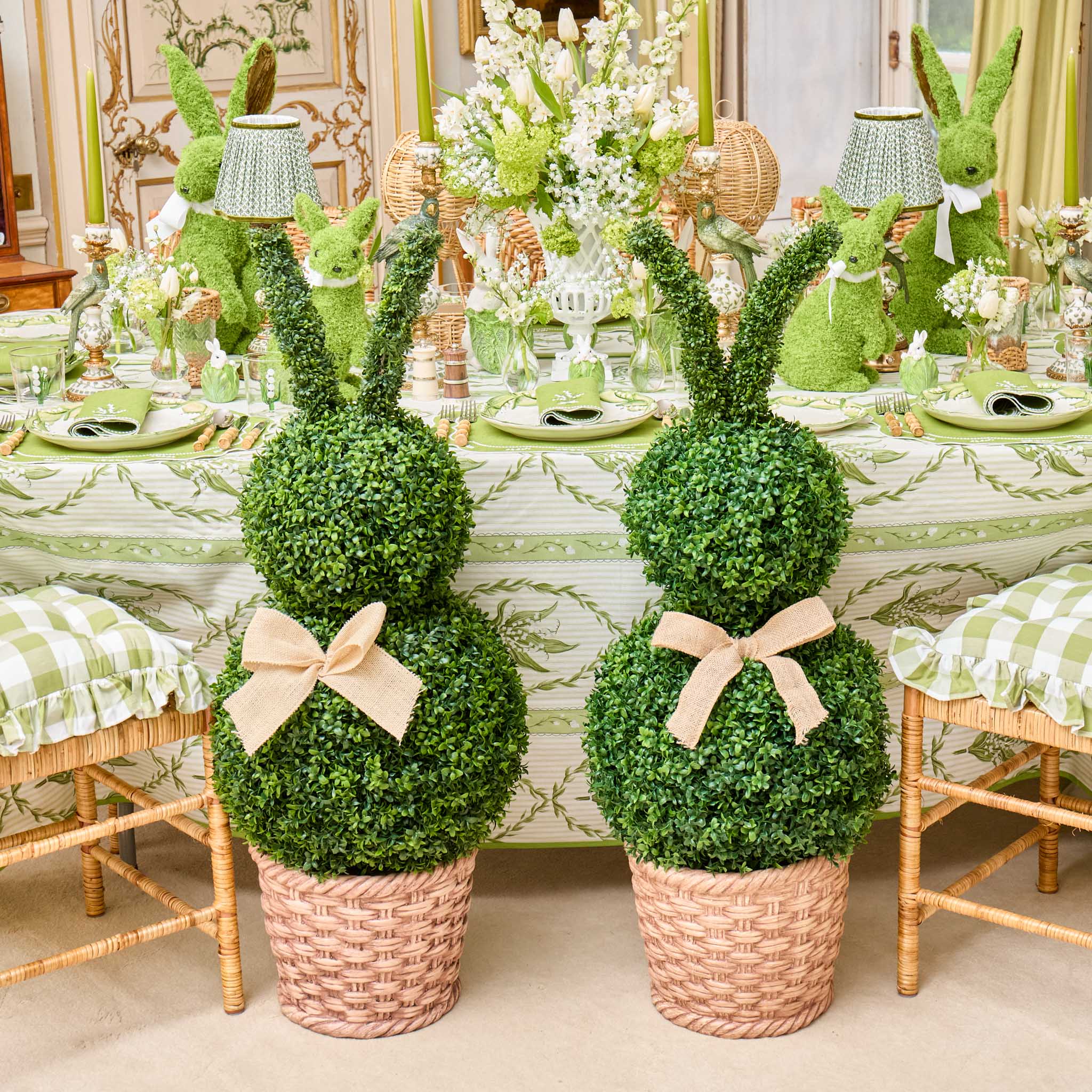 Decorative topiary rabbits with greenery on a table setting.