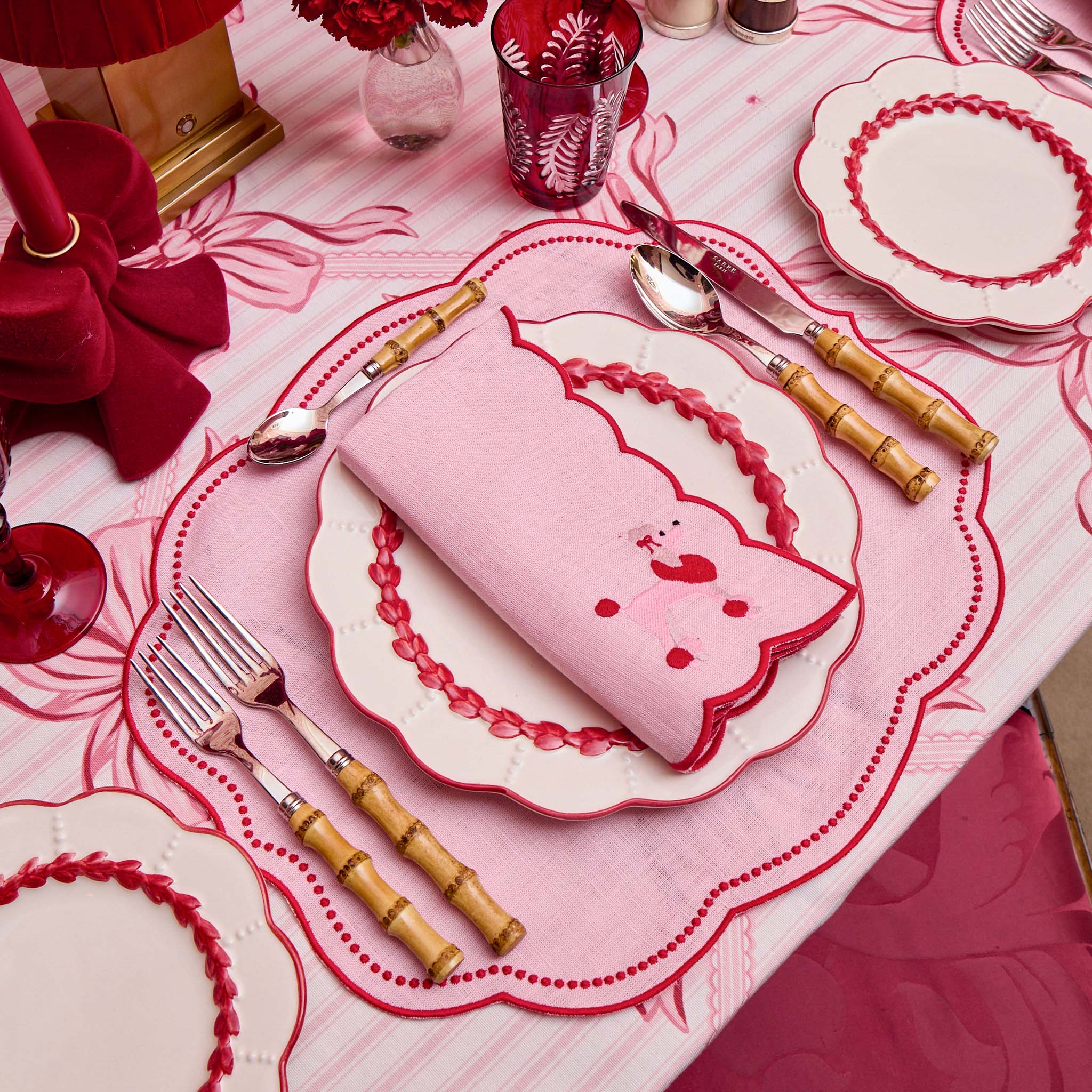 Pink table setting with Hello Kitty-themed napkin and cutlery on a matching pink tablecloth.