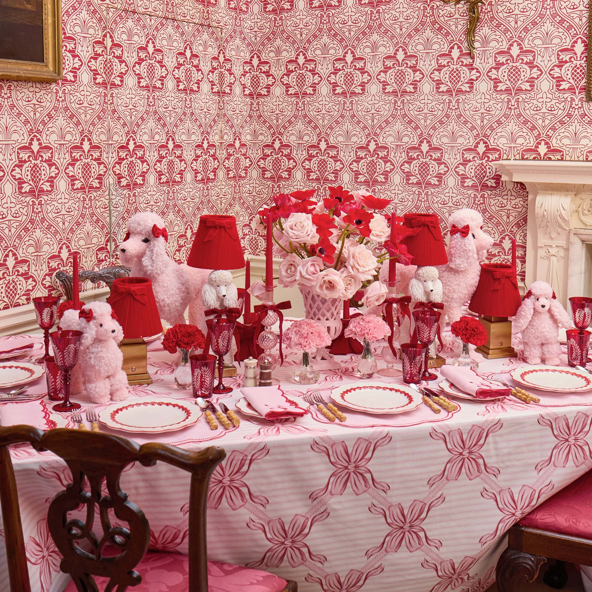 Dining room with a table set for a formal dinner, featuring red and white decor.