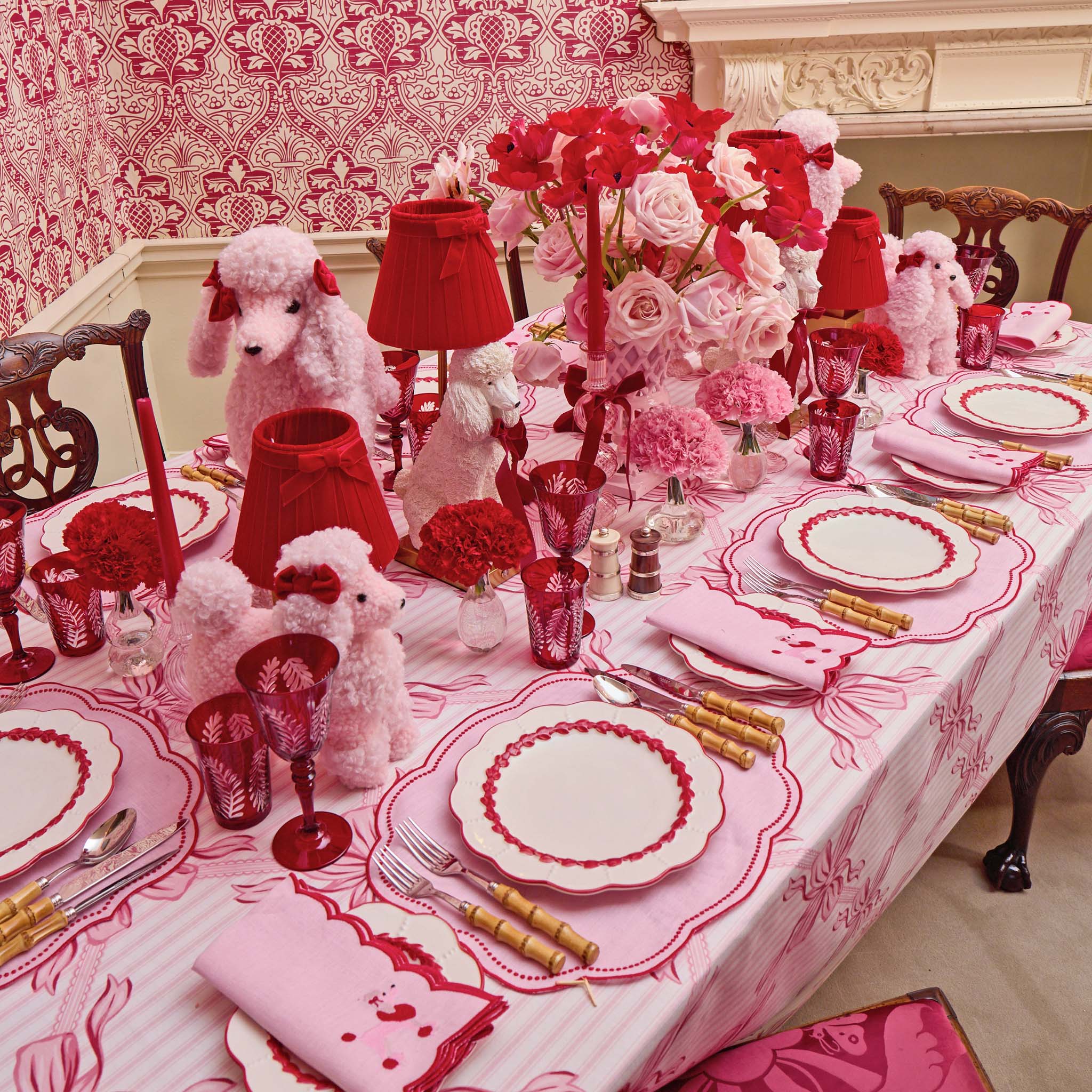 Decorative table setting with red and pink theme, including teddy bears and floral arrangements.