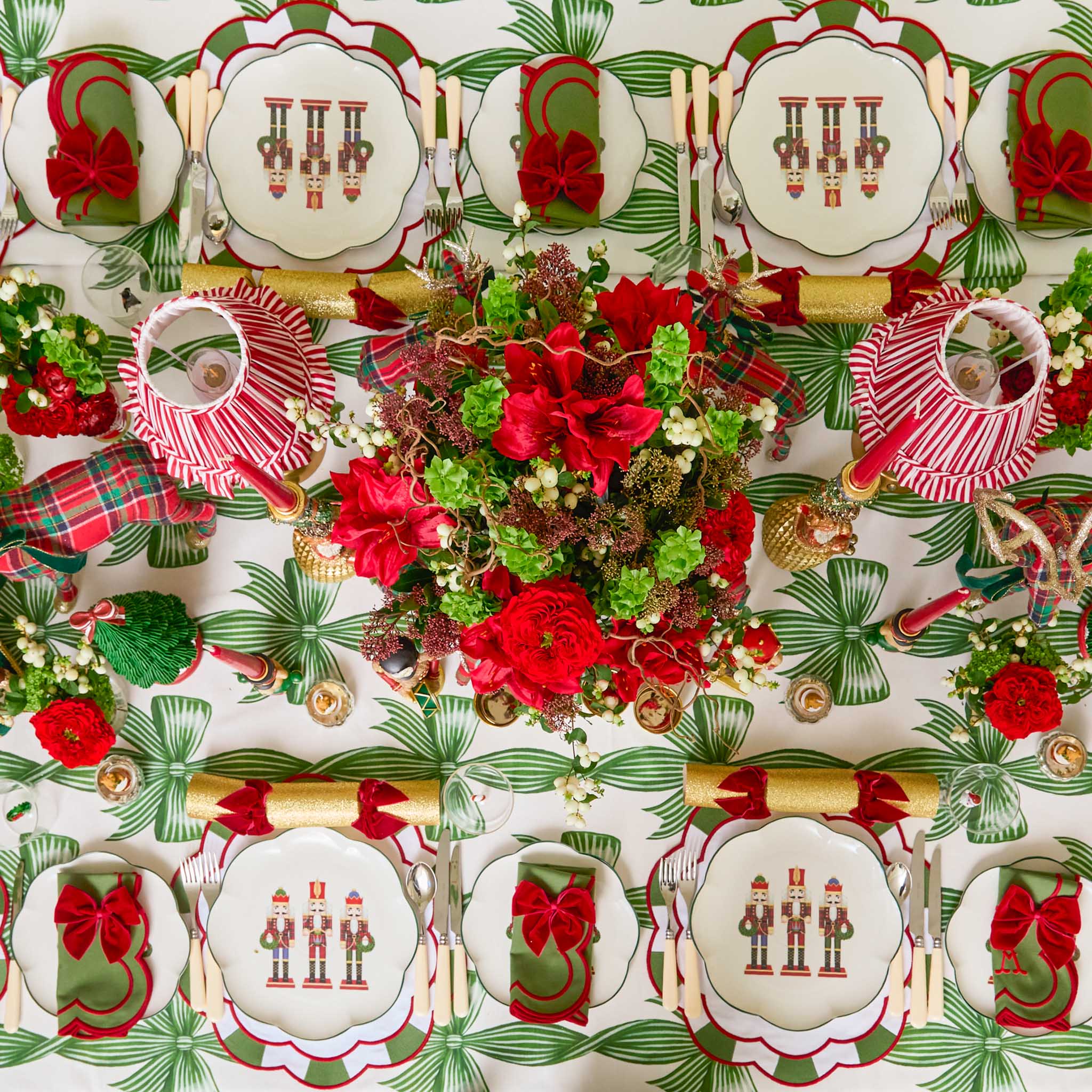 Patterned tablecloth with Christmas-themed design including plates, cutlery, and floral arrangement.