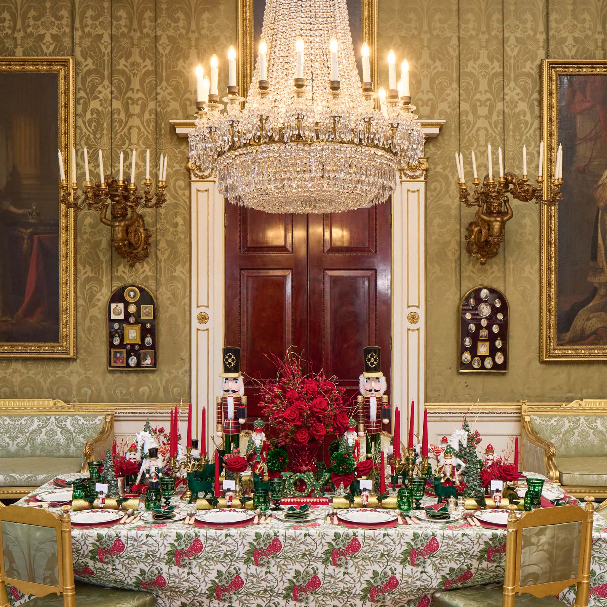 Decorative dining room with a table set for a festive meal, ornate chandelier, and classical wall art.
