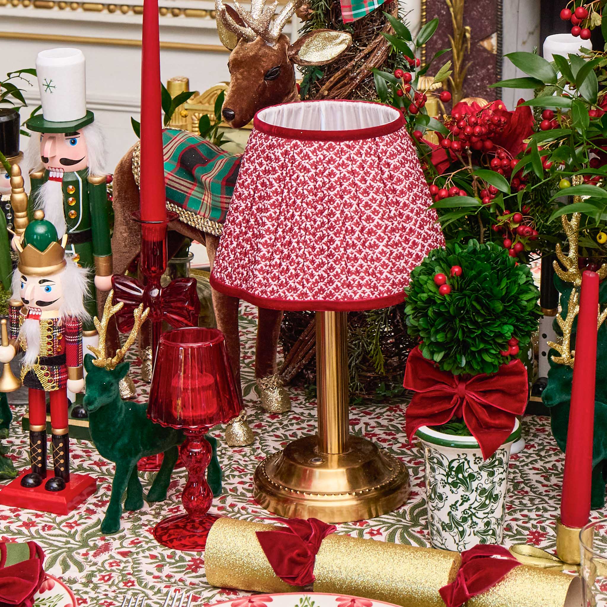 Decorative Christmas table setting with red and gold elements, including a lamp and nutcrackers.