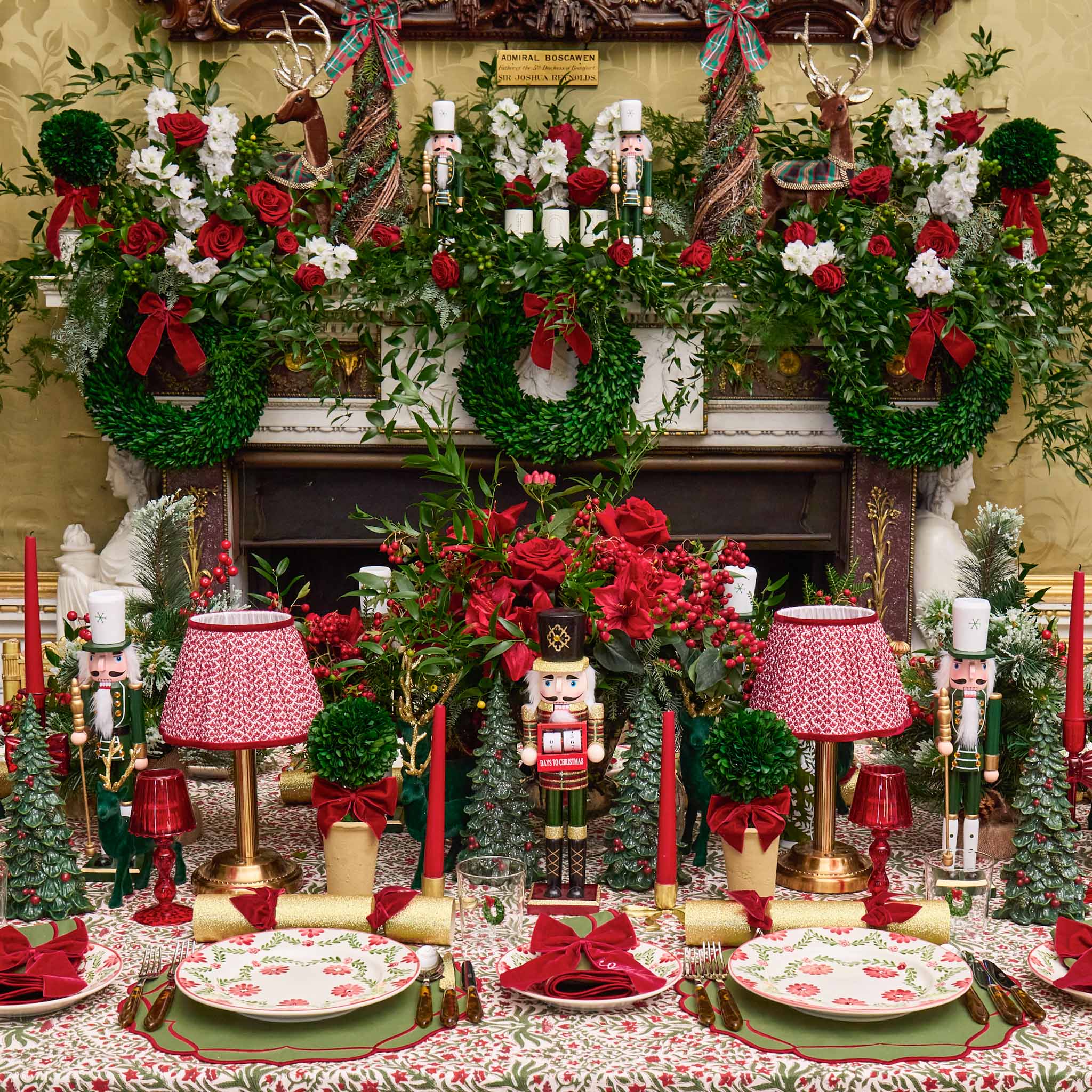 Decorative xmas table setting with red and green elements, including flowers and candles.
