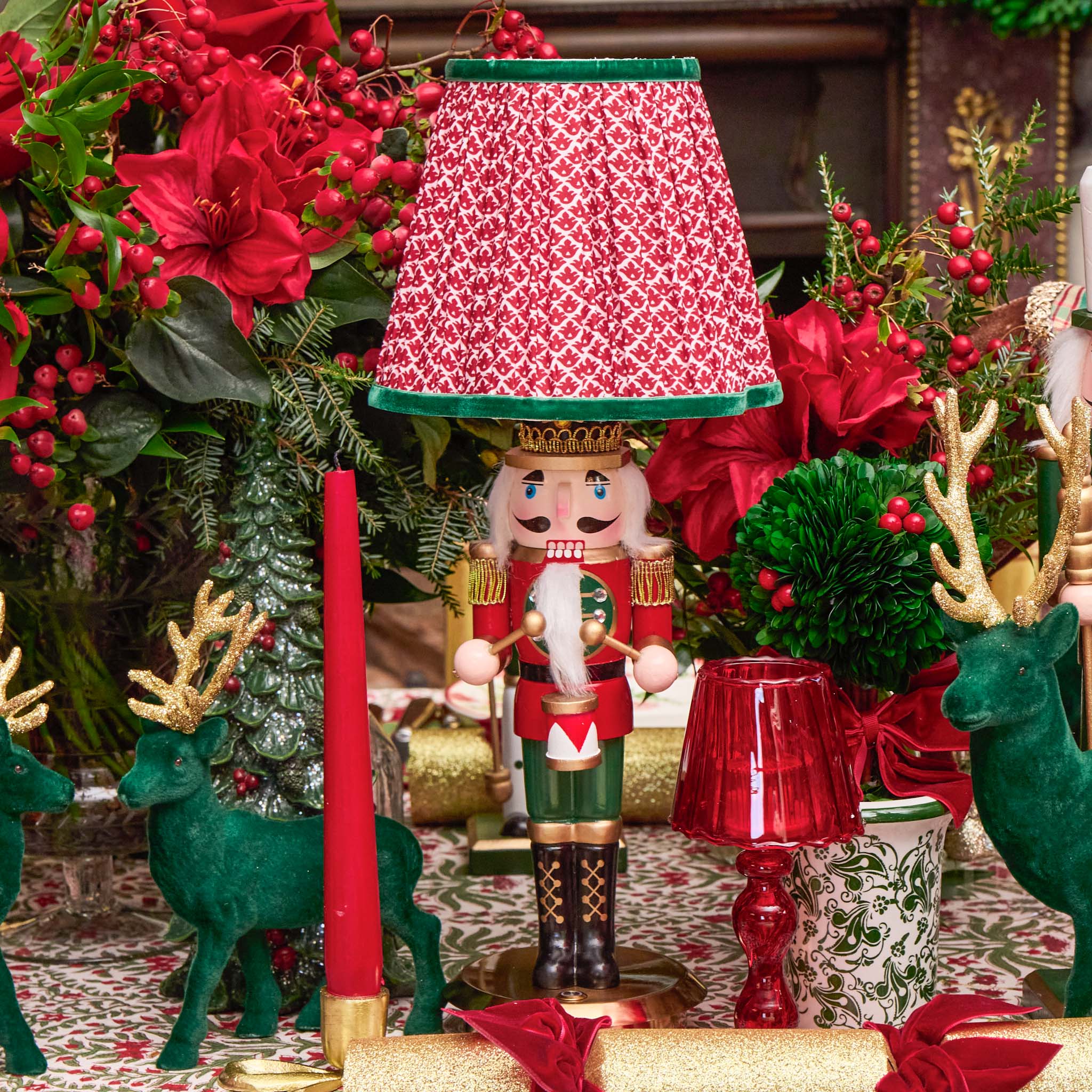 Decorative nutcracker with red and white checkered lampshade surrounded by Christmas decorations.