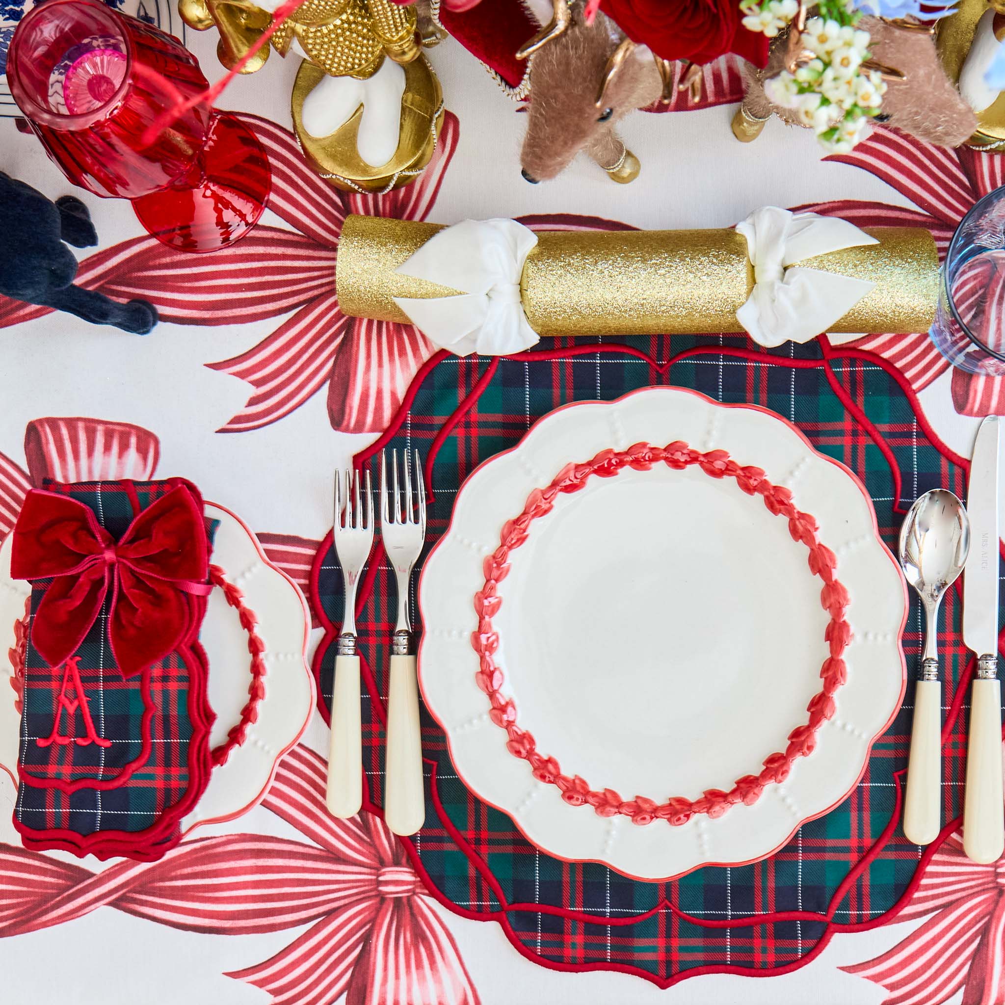 Decorative Christmas table setting with plaid tablecloth, red and white plates, and festive decorations.