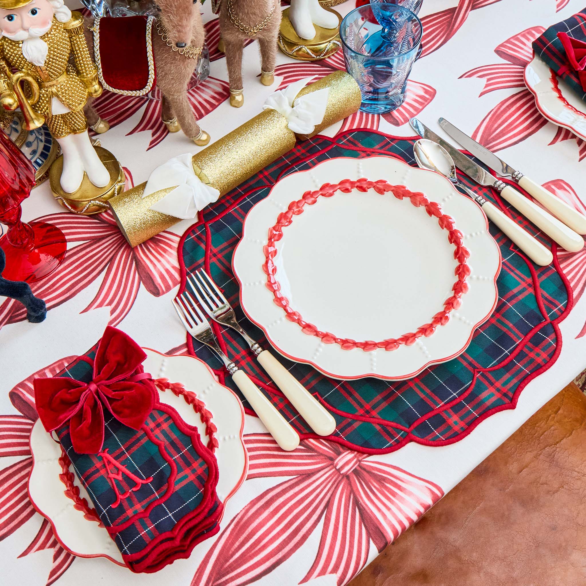 Decorative Christmas table setting with plaid placemats, red and white plates, and festive decorations.