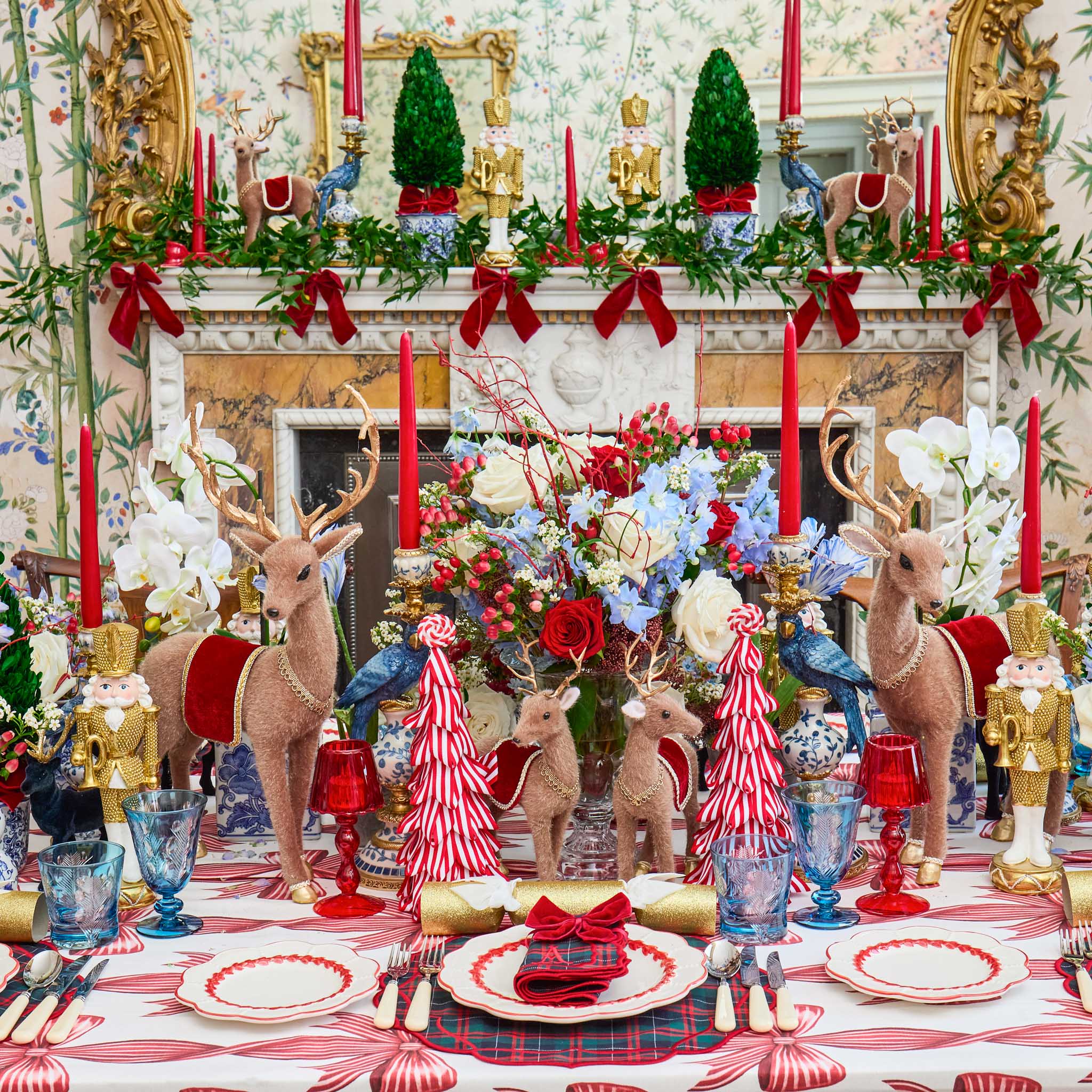 Decorative Christmas table setting with reindeer, candles, and floral arrangements.