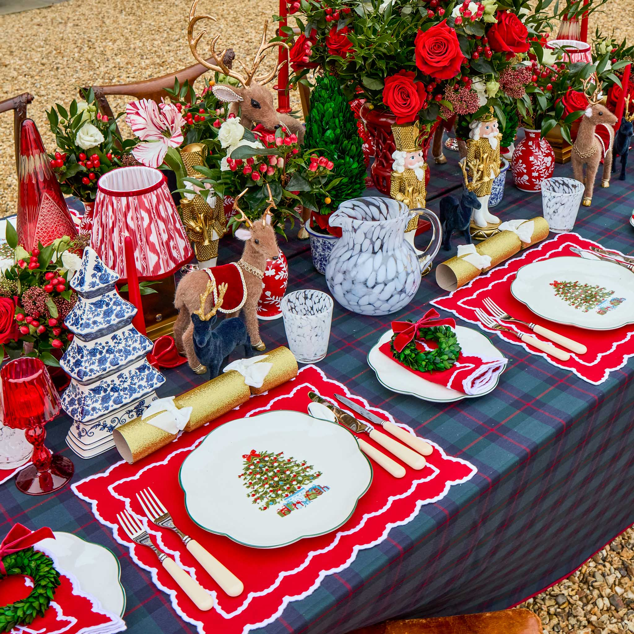 Decorative Christmas table setting with red and white tablecloth, place settings, and festive decorations.