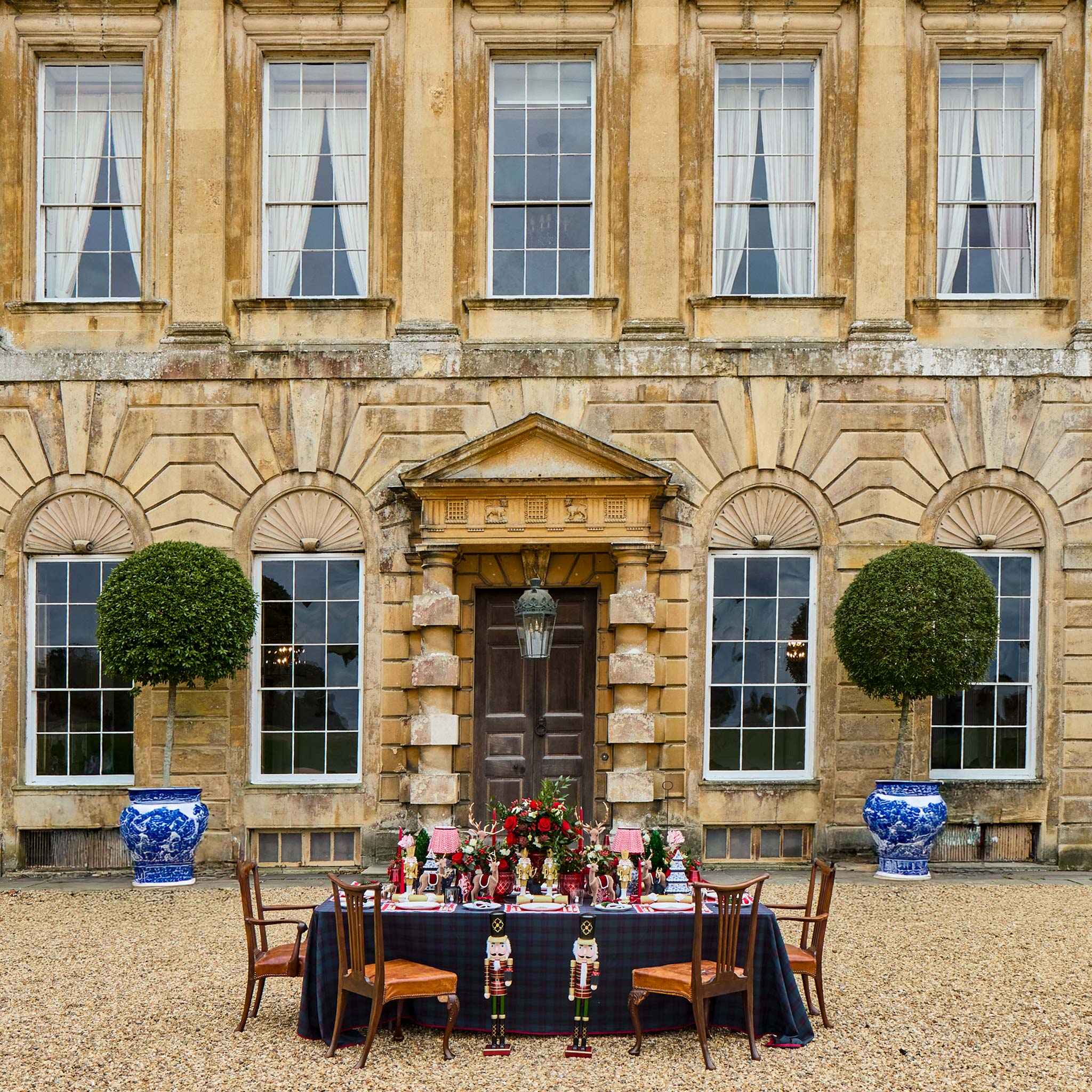 Table set for a formal event in front of a grand stone building with decorative vases.