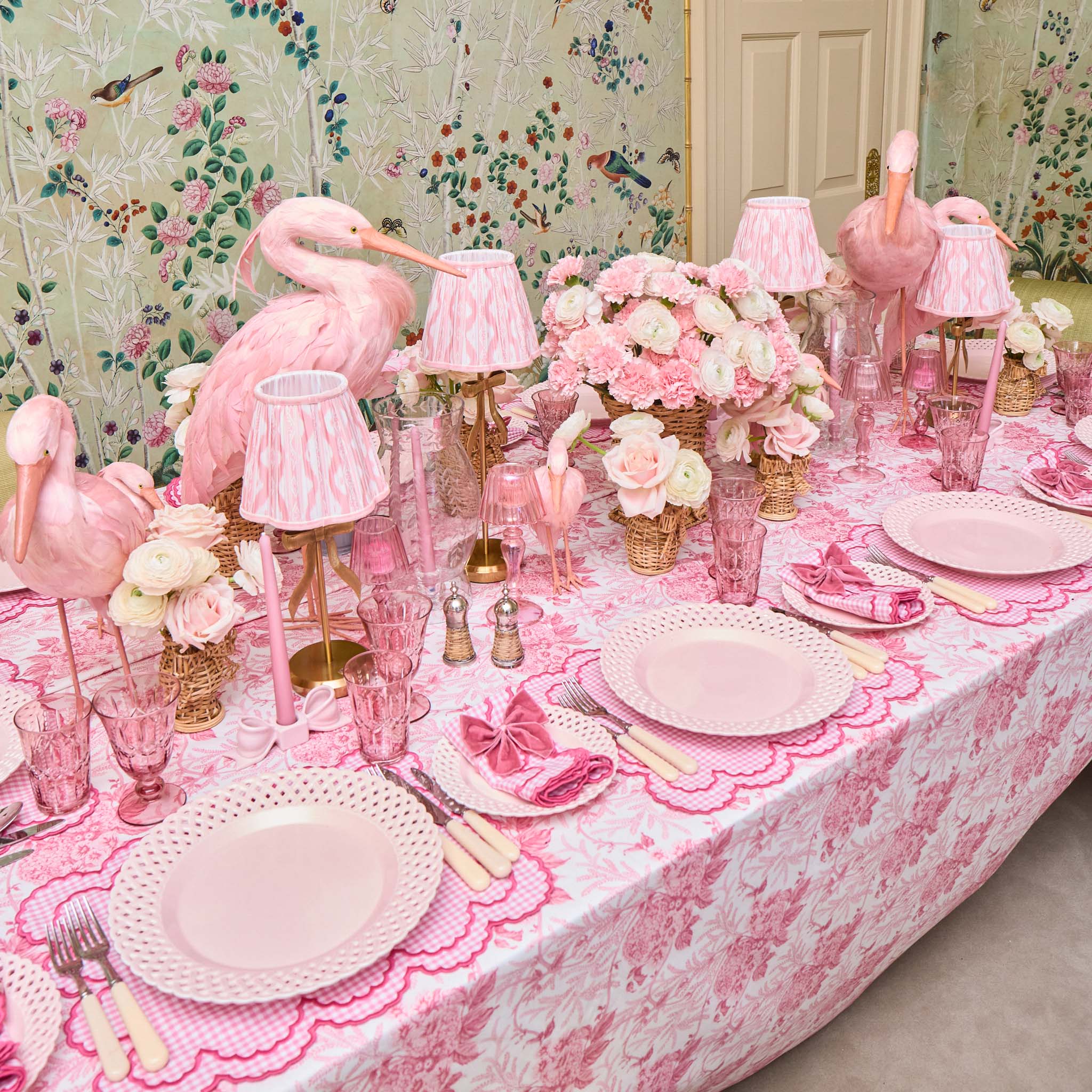 Decorative table setting with pink flamingo decorations and floral arrangements.
