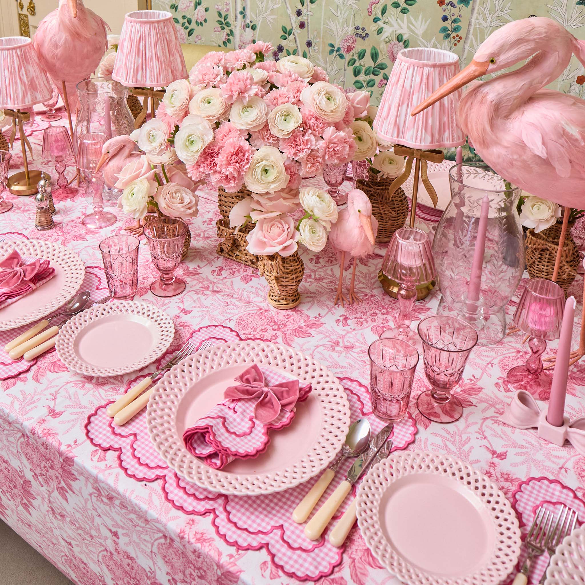 Pink and white floral centerpiece on a decorated table with matching tablecloth and decor.