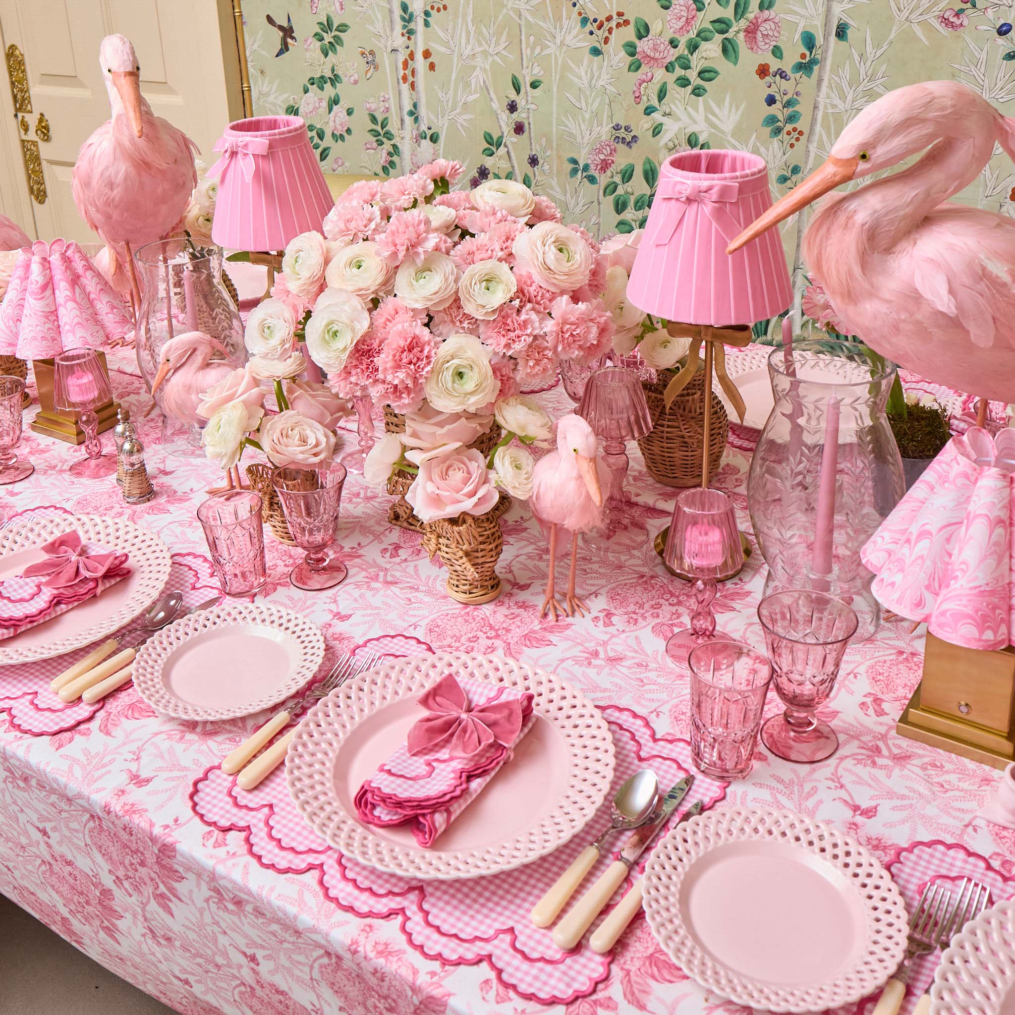 Pink-themed table setting with flamingo decorations and floral arrangements.