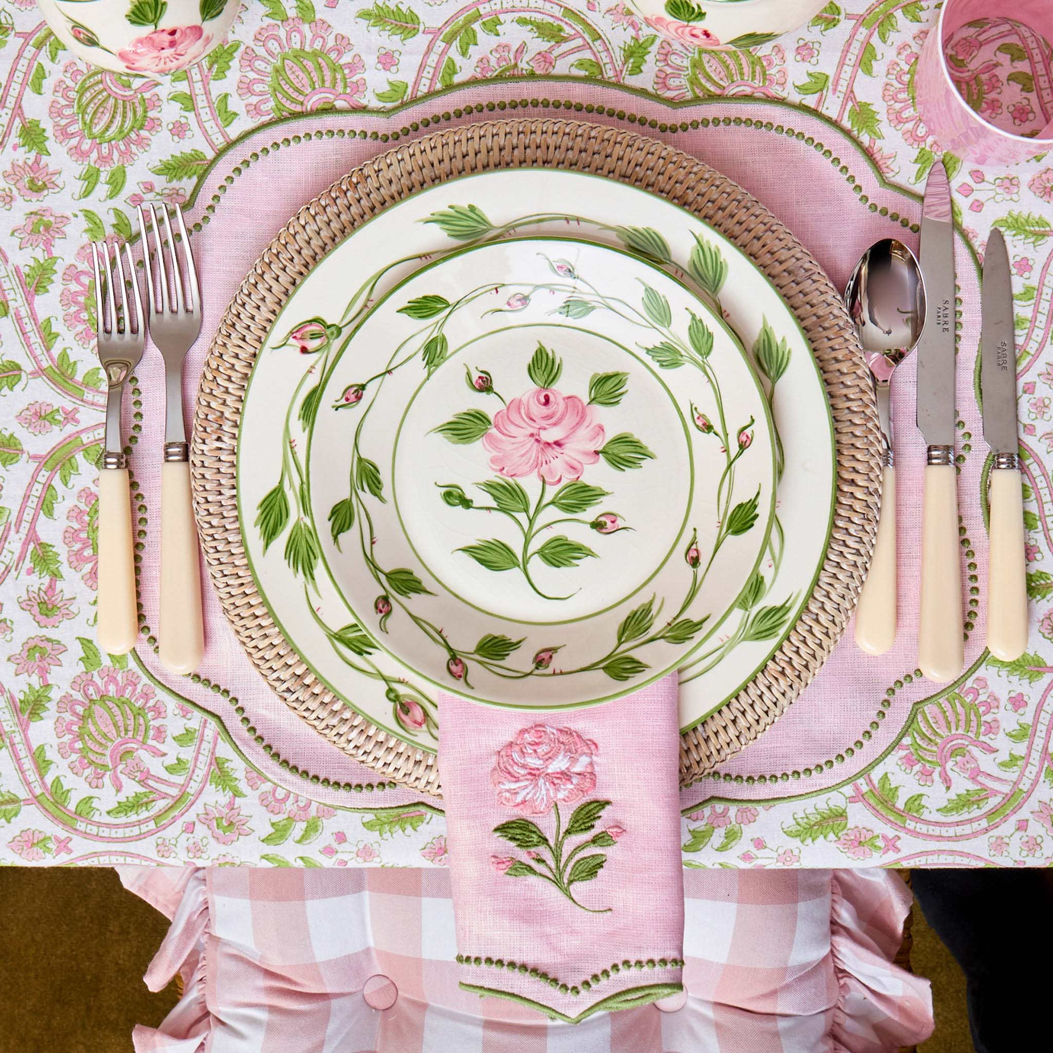 Table setting with floral plates, cutlery, and napkins on a matching tablecloth.