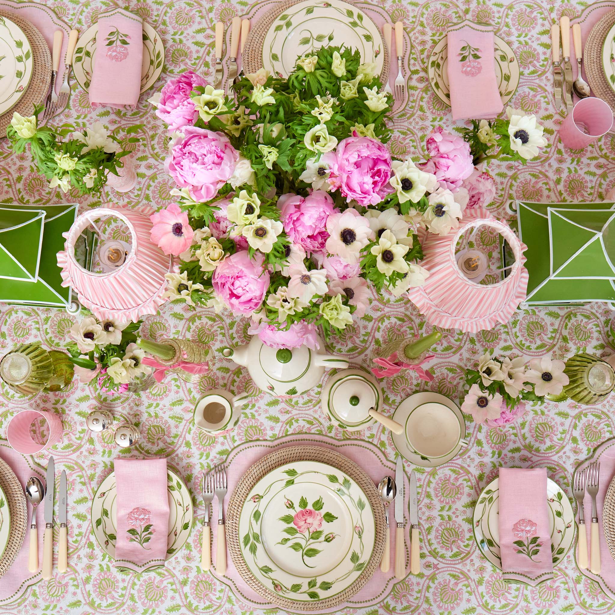 Elegant table setting with floral centerpieces, pink and green tablecloth, and decorative plates.