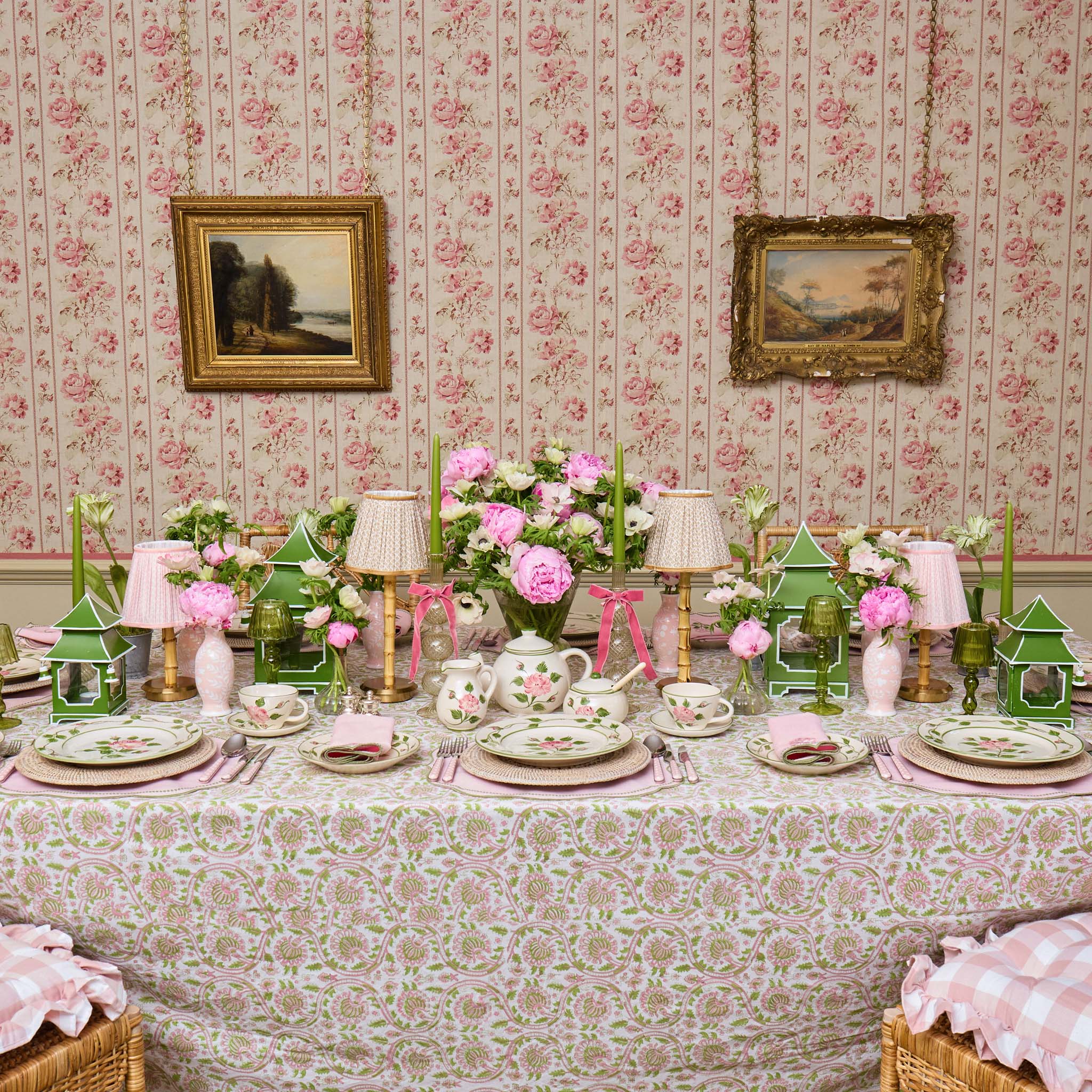 Decorative table setting with floral wallpaper and framed pictures.