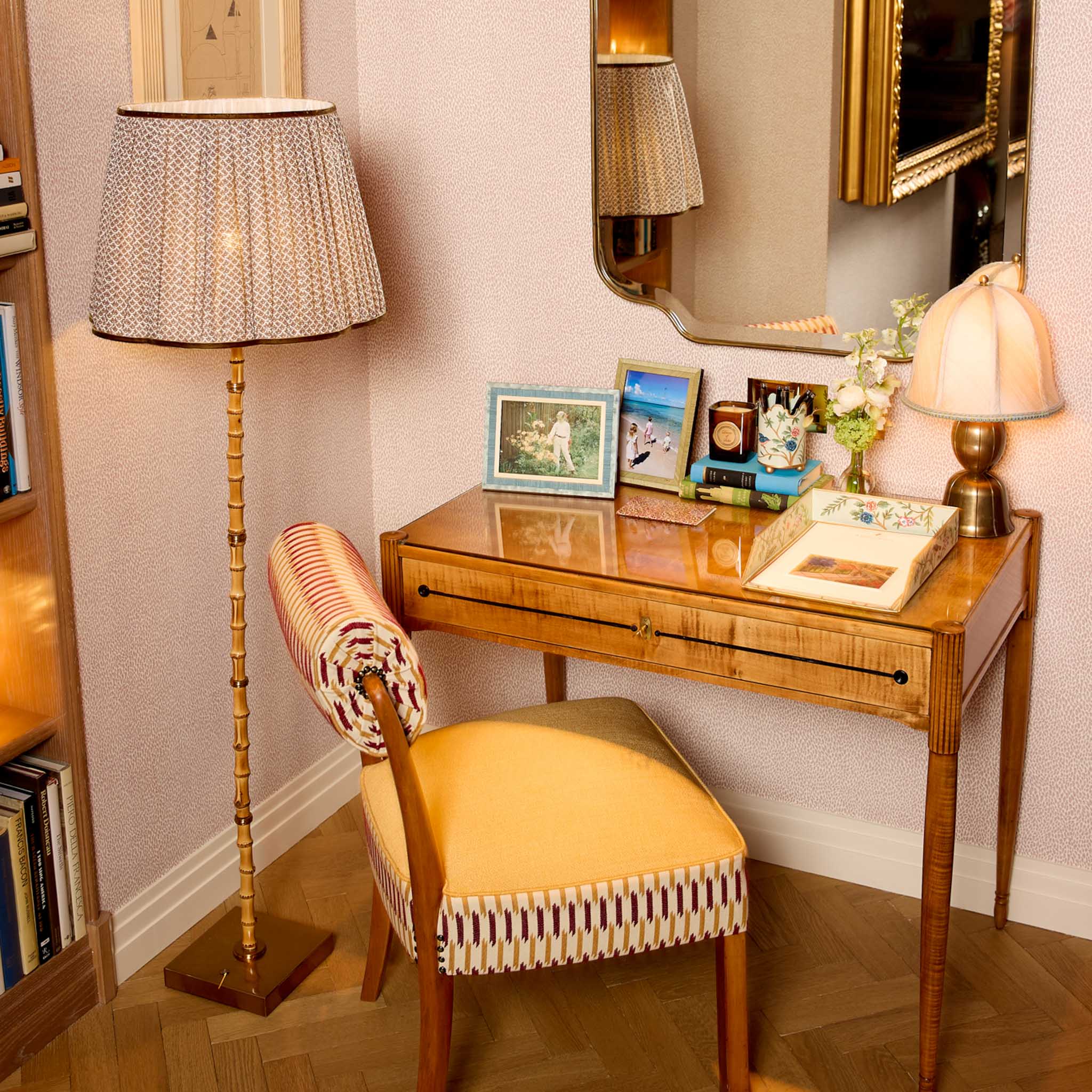 Small wooden desk with chair, lamp, and decorative items in a room.