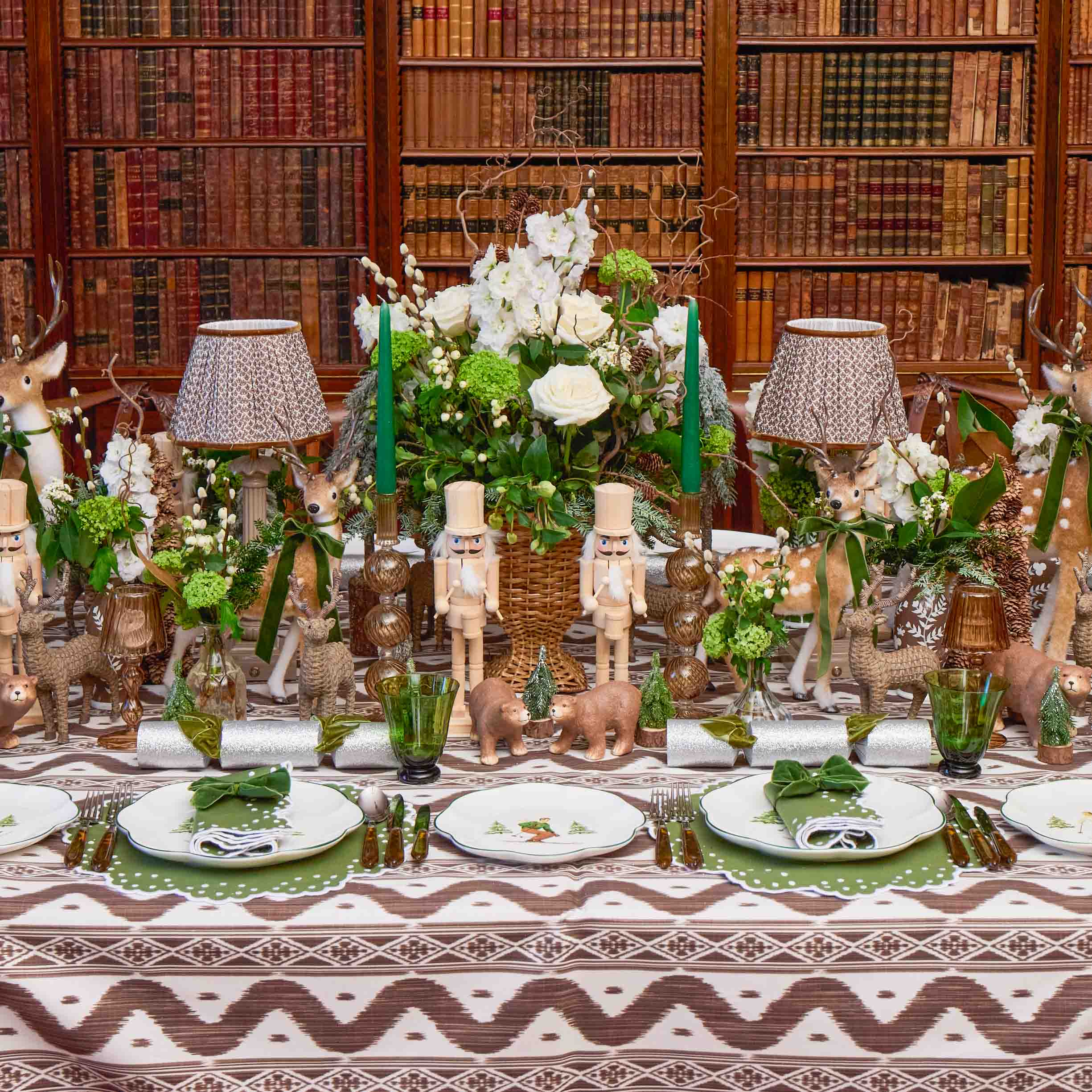 Decorative table setting with floral arrangements, candles, and small figurines in a library setting.