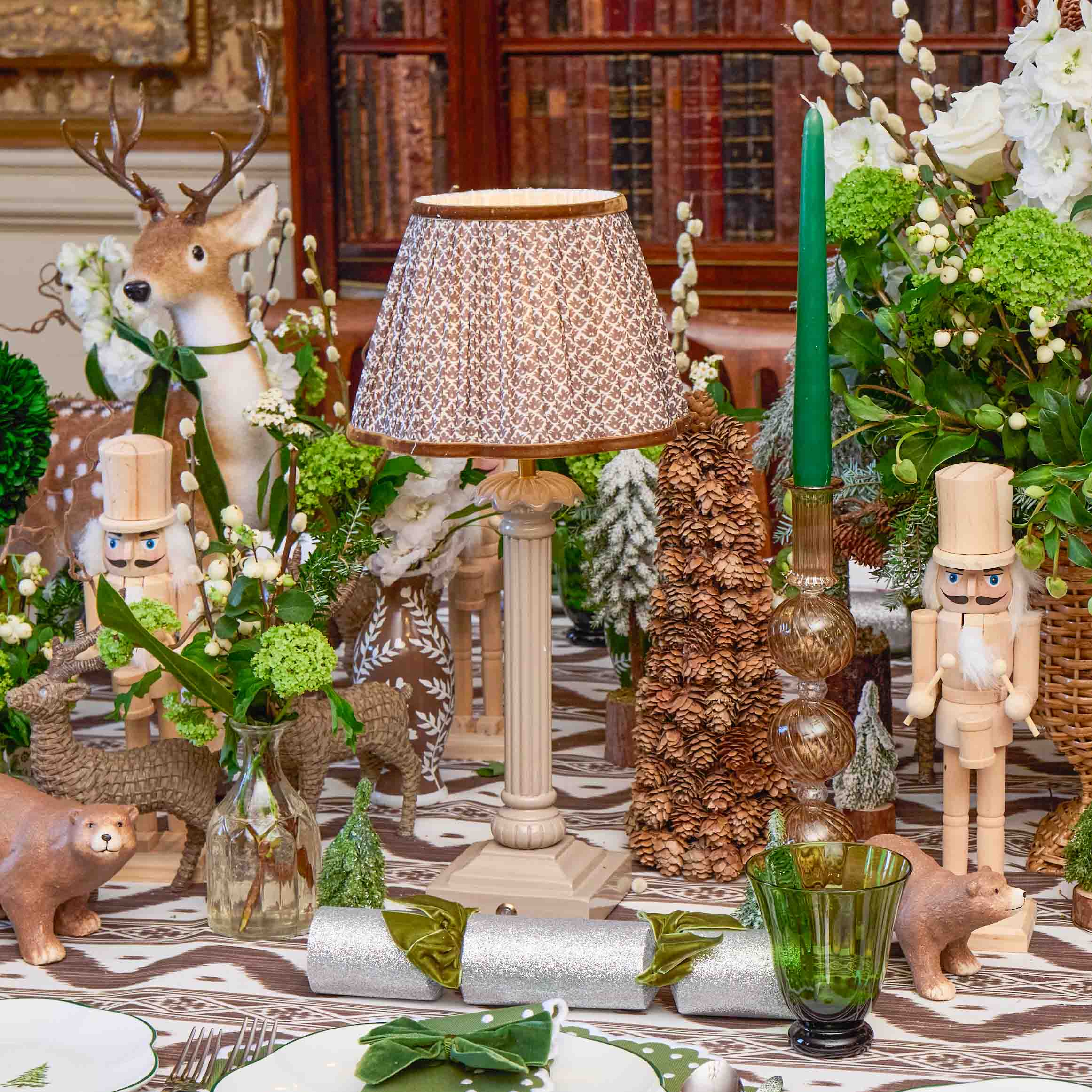 Decorative table setting with a lamp, flowers, and small figurines in a room with wooden paneling.