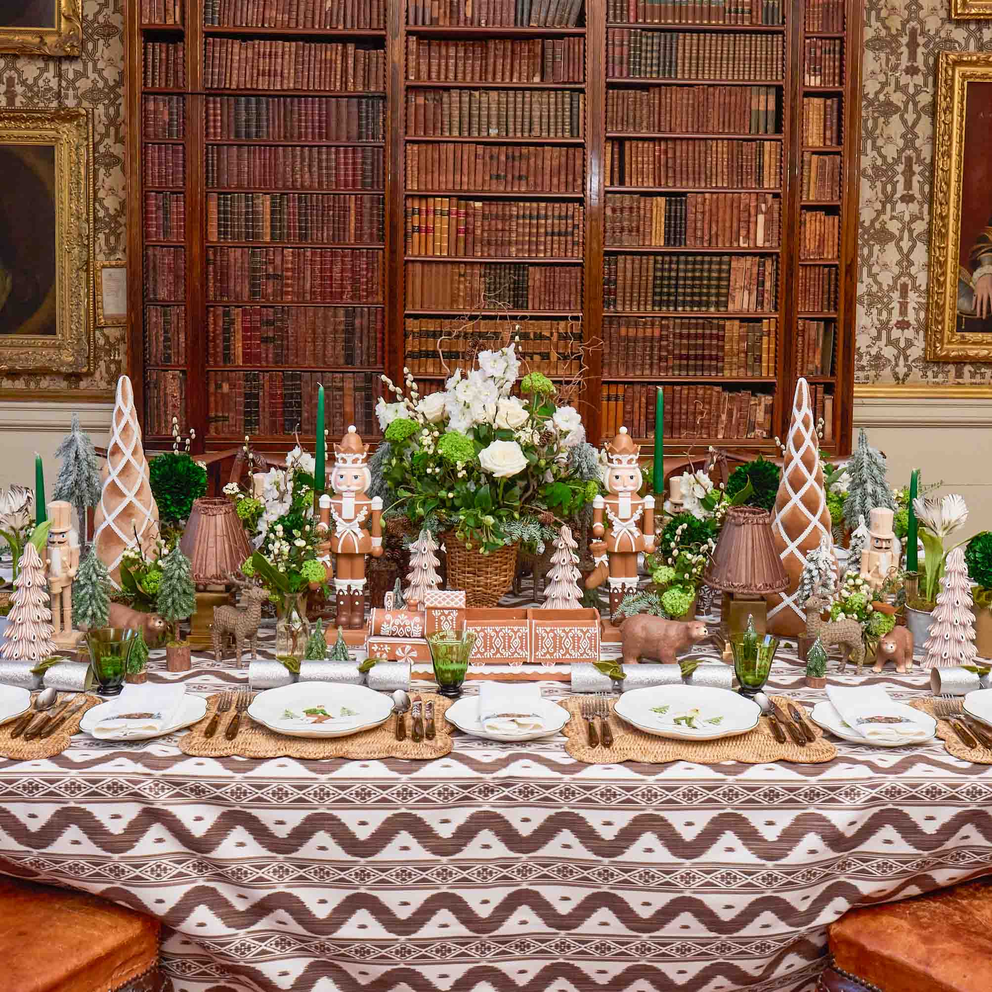 Decorative table setting with nutcrackers and floral arrangements in a room with bookshelves.